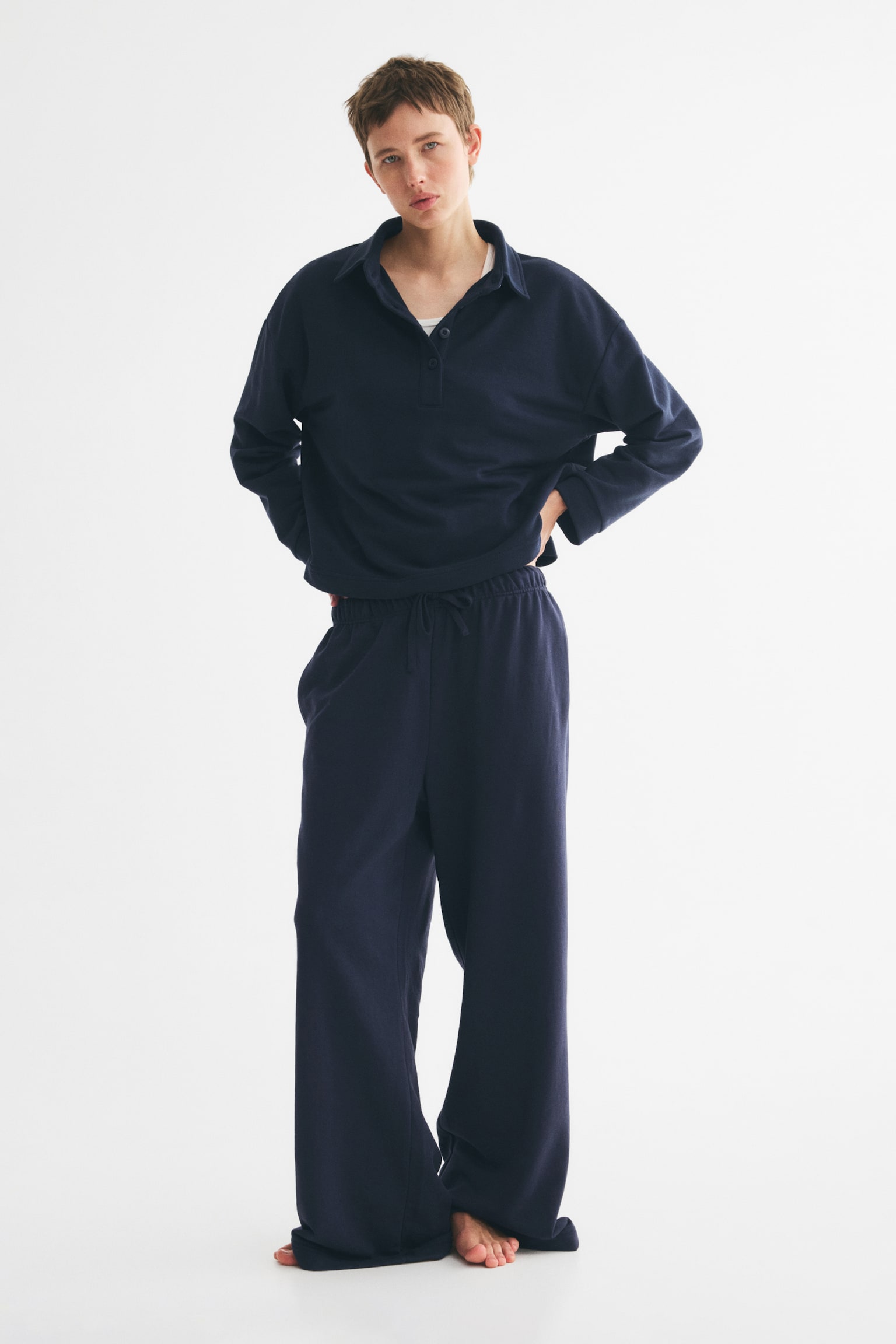 Navy blue joggers are showcased from a front perspective, highlighting an elasticated waistband with a drawstring fastening. These joggers are crafted with straight legs in a lightweight sweatshirt material. - 1