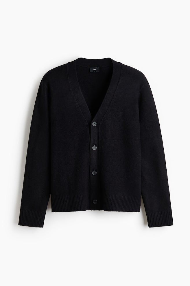 A black cardigan is displayed front-facing, featuring a V-neckline, a five-button front closure, long sleeves with ribbed cuffs, and a ribbed hem. - 1