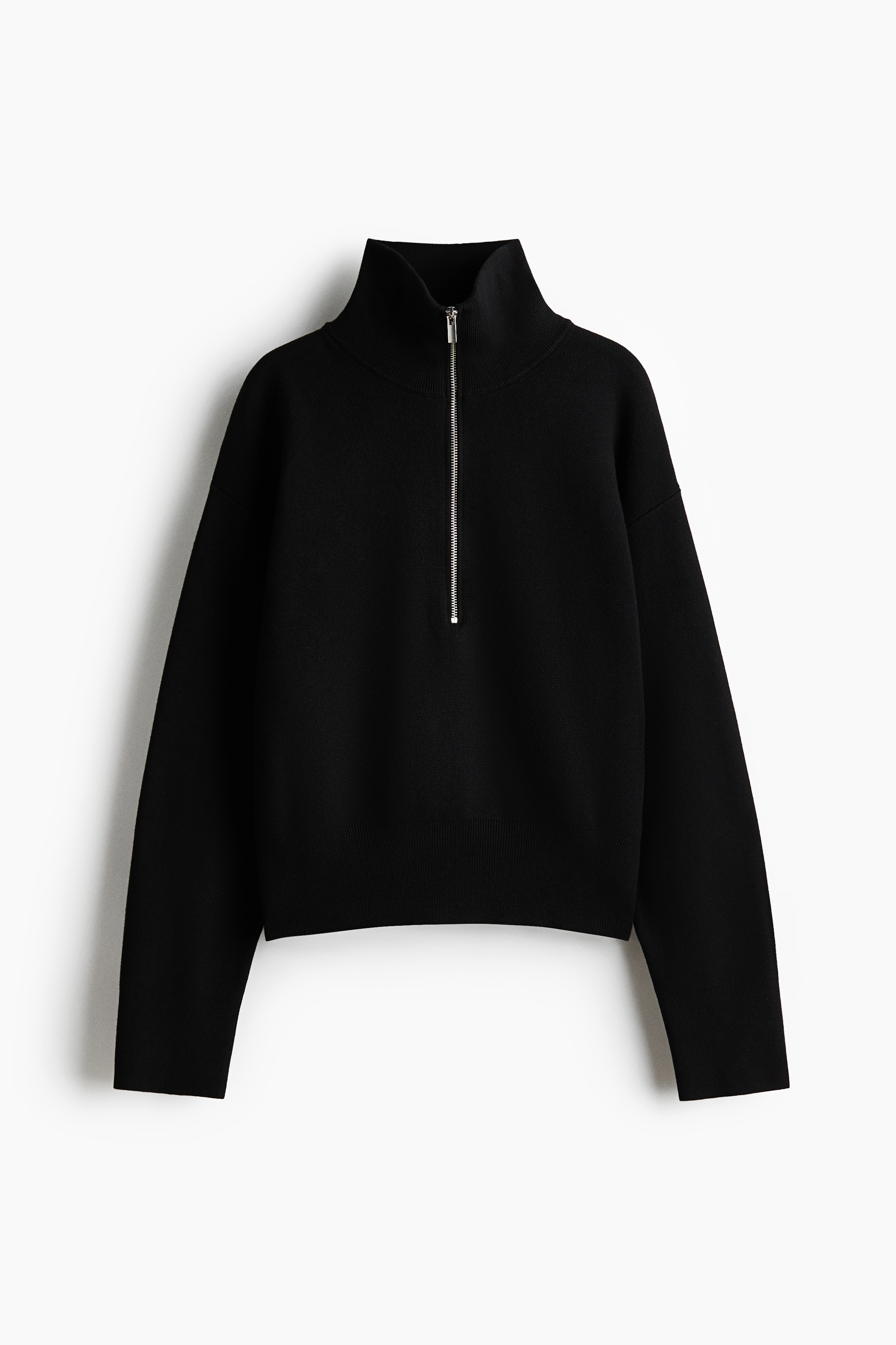 Un pull noir en maille fine, dotÃ© dâun col zippÃ© Ã  mi-hauteur et dâÃ©paules tombantes, est portÃ© par le mannequin. Le pull est stylÃ© ouvert sur un t-shirt blanc Ã  col rond et associÃ© Ã  un pantalon noir assorti.