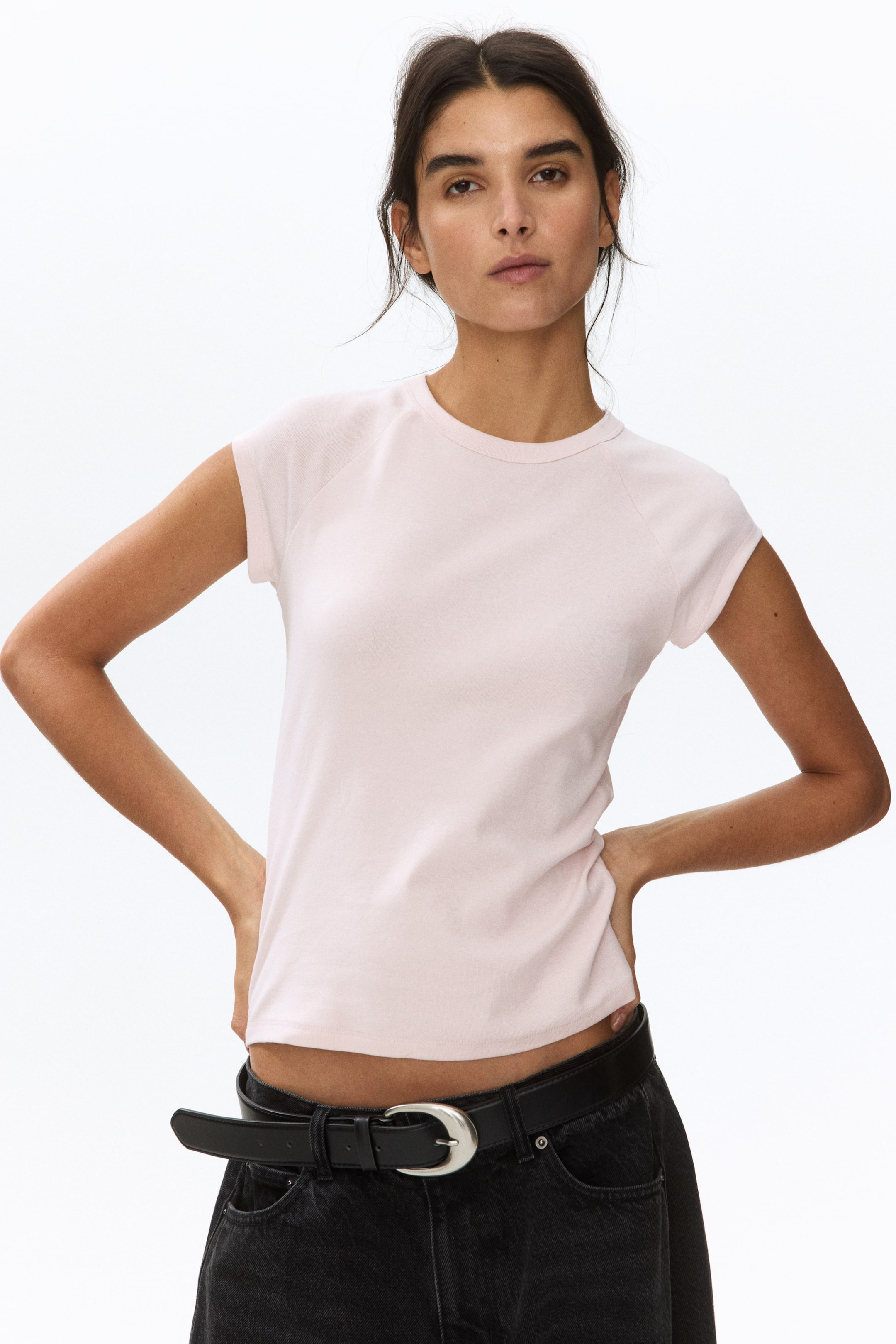 拡大画像を表示: ライトピンクのTシャツは、クルーネック、ラグランショートスリーブ、滑らかな生地の質感を特徴としており、セミフィットのシルエットを演出します。