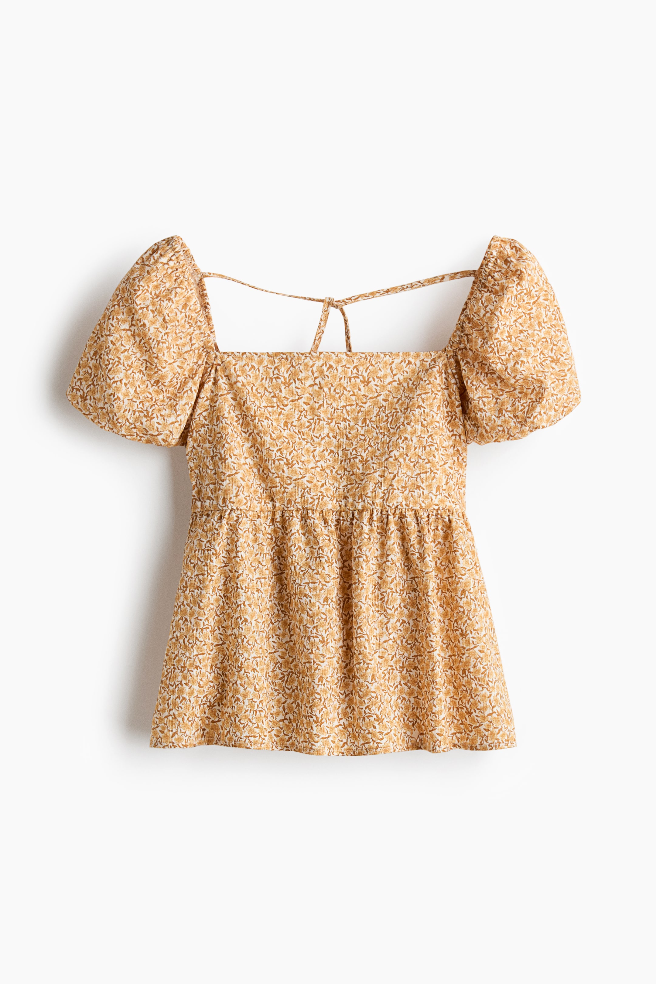 View larger image: A FRONT view of a light tan top with a small floral print is featuring a square neckline, voluminous short sleeves, and an empire waistline with gathering. Thin straps are extending from the back neckline, arching towards the center back.