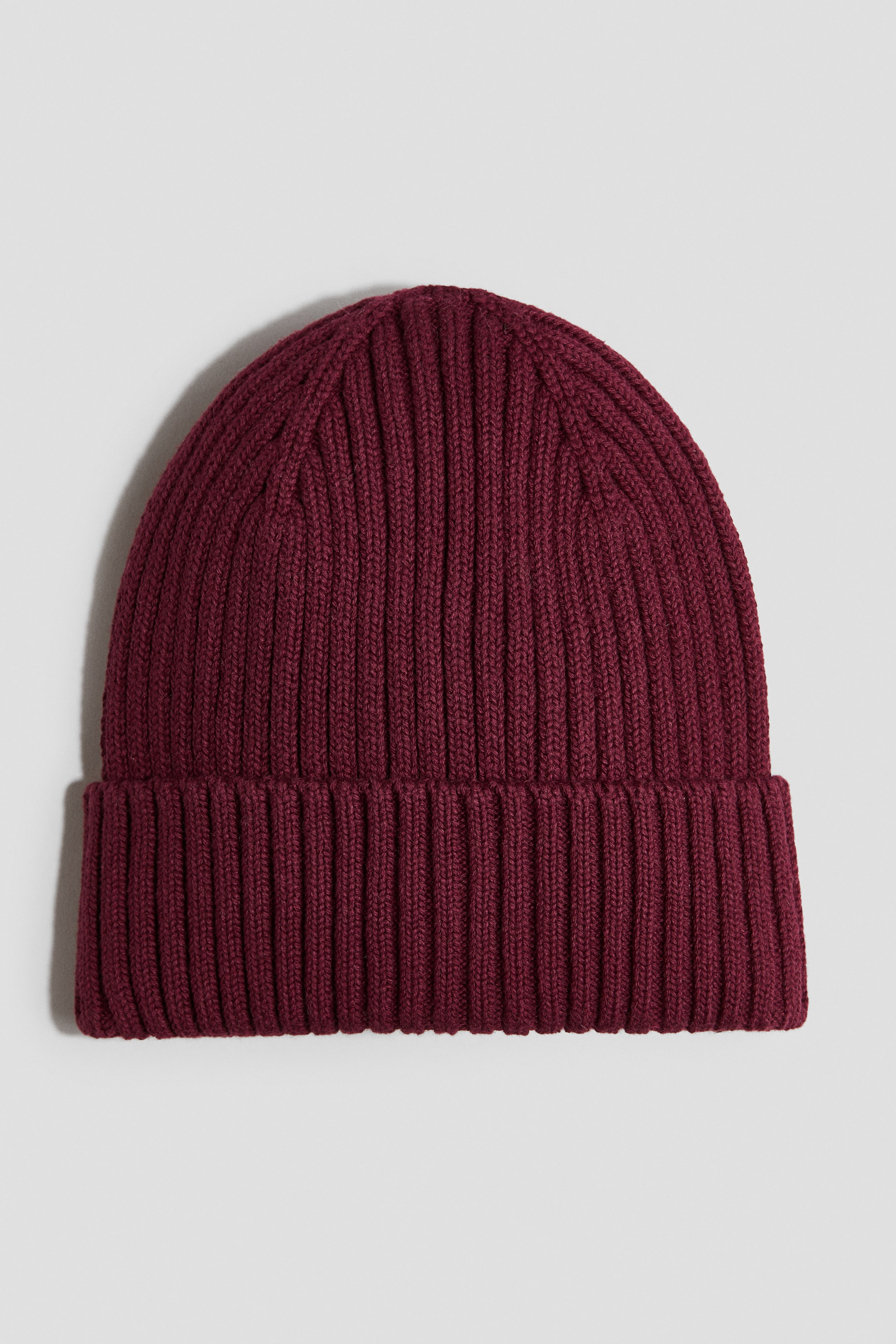View larger image: A dark red beanie is shown from the front, featuring a soft ribbed knit and a fold-up cuff at the hem.