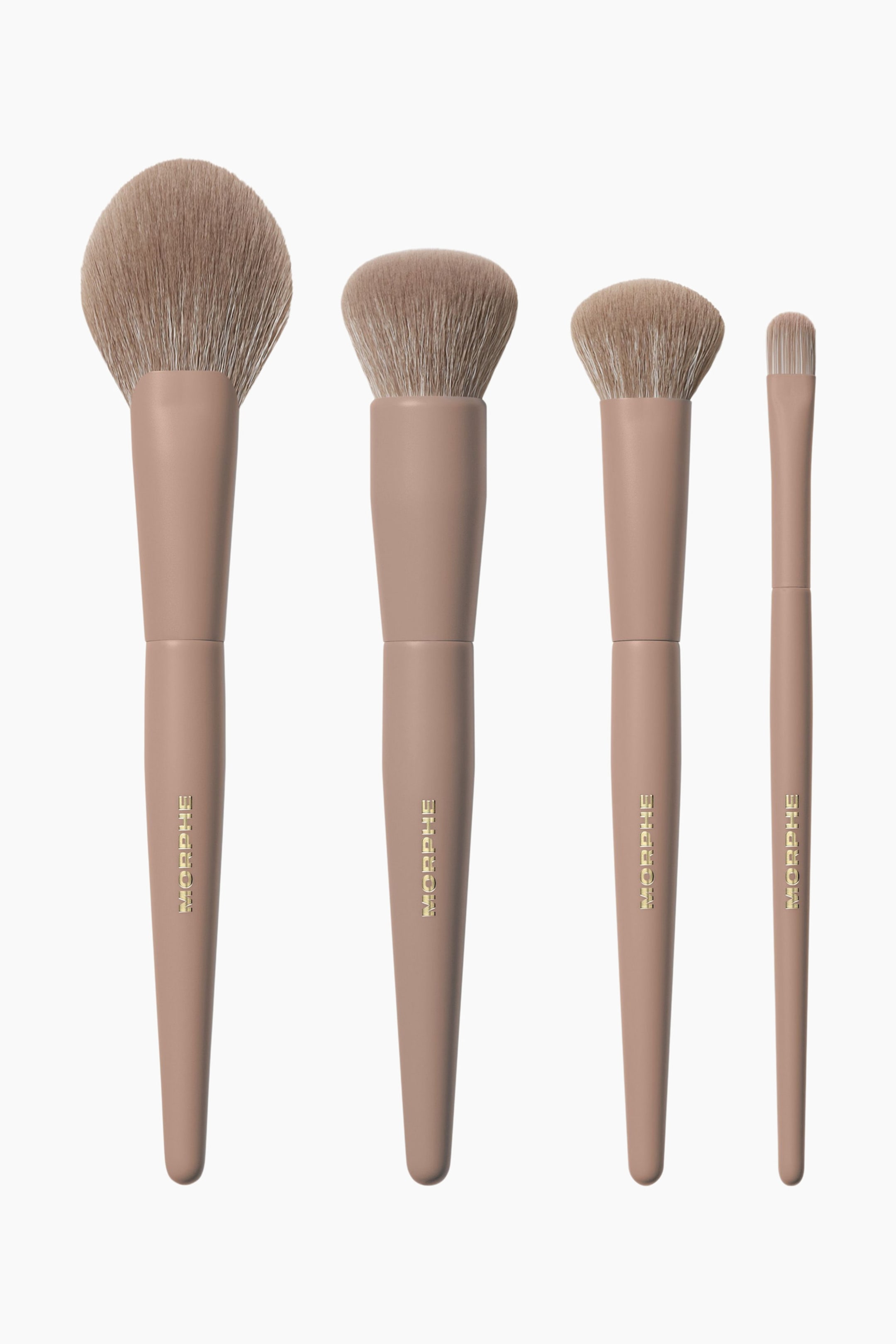 Se større billede: Fire Morphe makeupbørster står oprejst, vendt fremad, hver med et lysebrunt håndtag med guldfarvet branding og lysebrune børstehår. Sættet inkluderer en stor fluffy børste, en mellemstor kuplet børste, en mindre tilspidset børste og en lille flad børste.