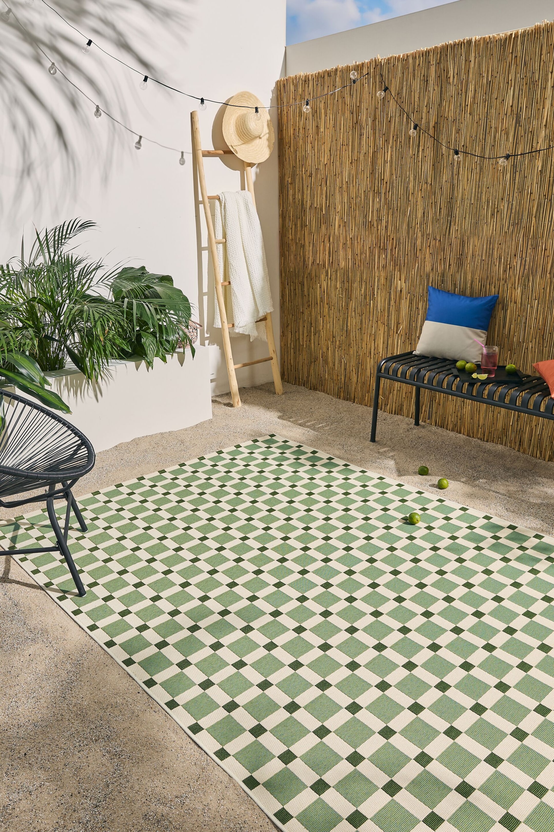 Ver imagen más grande: Una alfombra rectangular muestra un patrón geométrico de cuadrados verde claro dispuestos dentro de una cuadrícula blanco roto. Cuadrados más pequeños de color verde oscuro están colocados en las intersecciones de la cuadrícula.