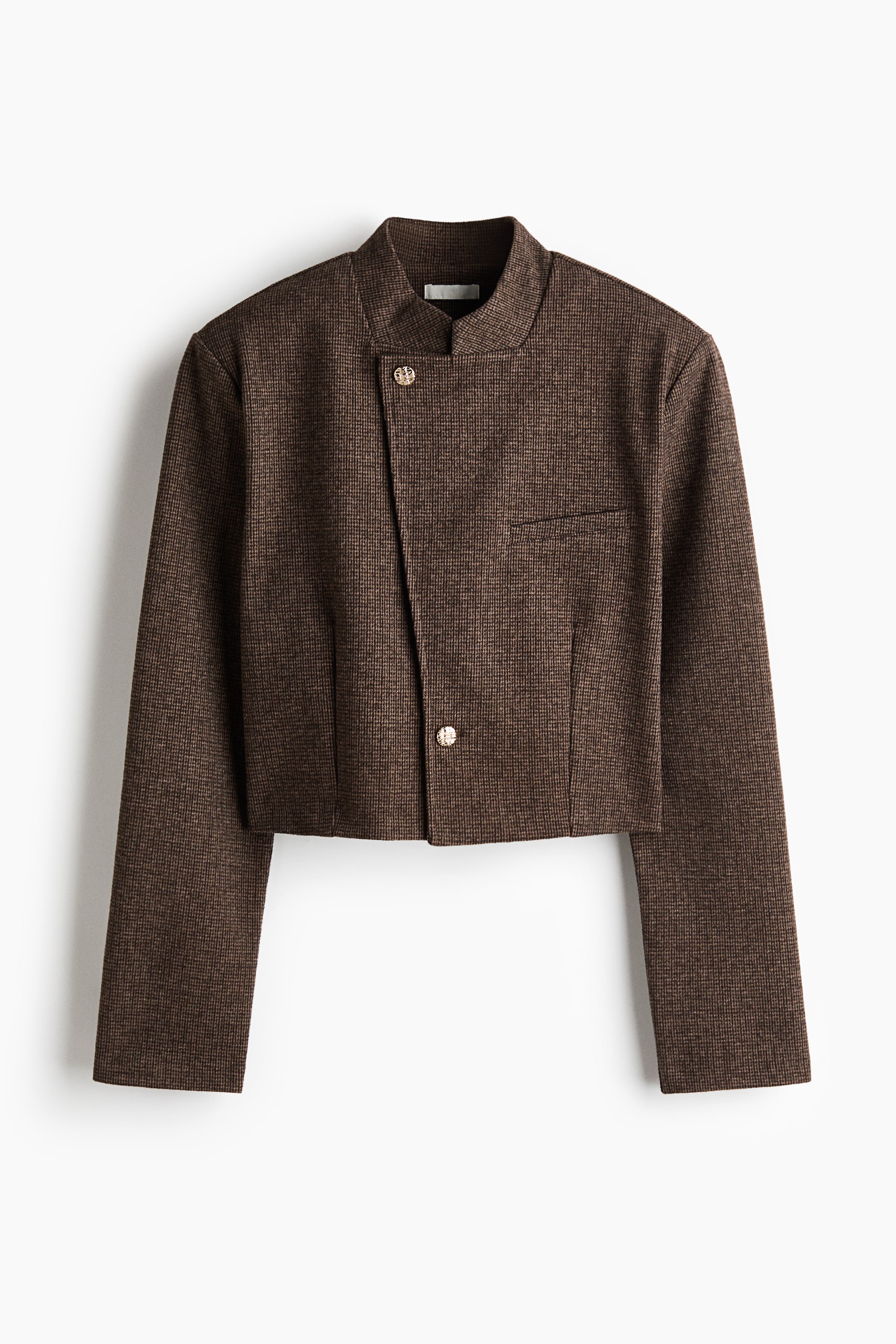 View larger image: A cropped, textured brown jacket features a fine checkered pattern and an asymmetrical front closure with two round metallic buttons. The jacket has a high stand collar, structured shoulders, a single chest welt pocket, and long straight sleeves.