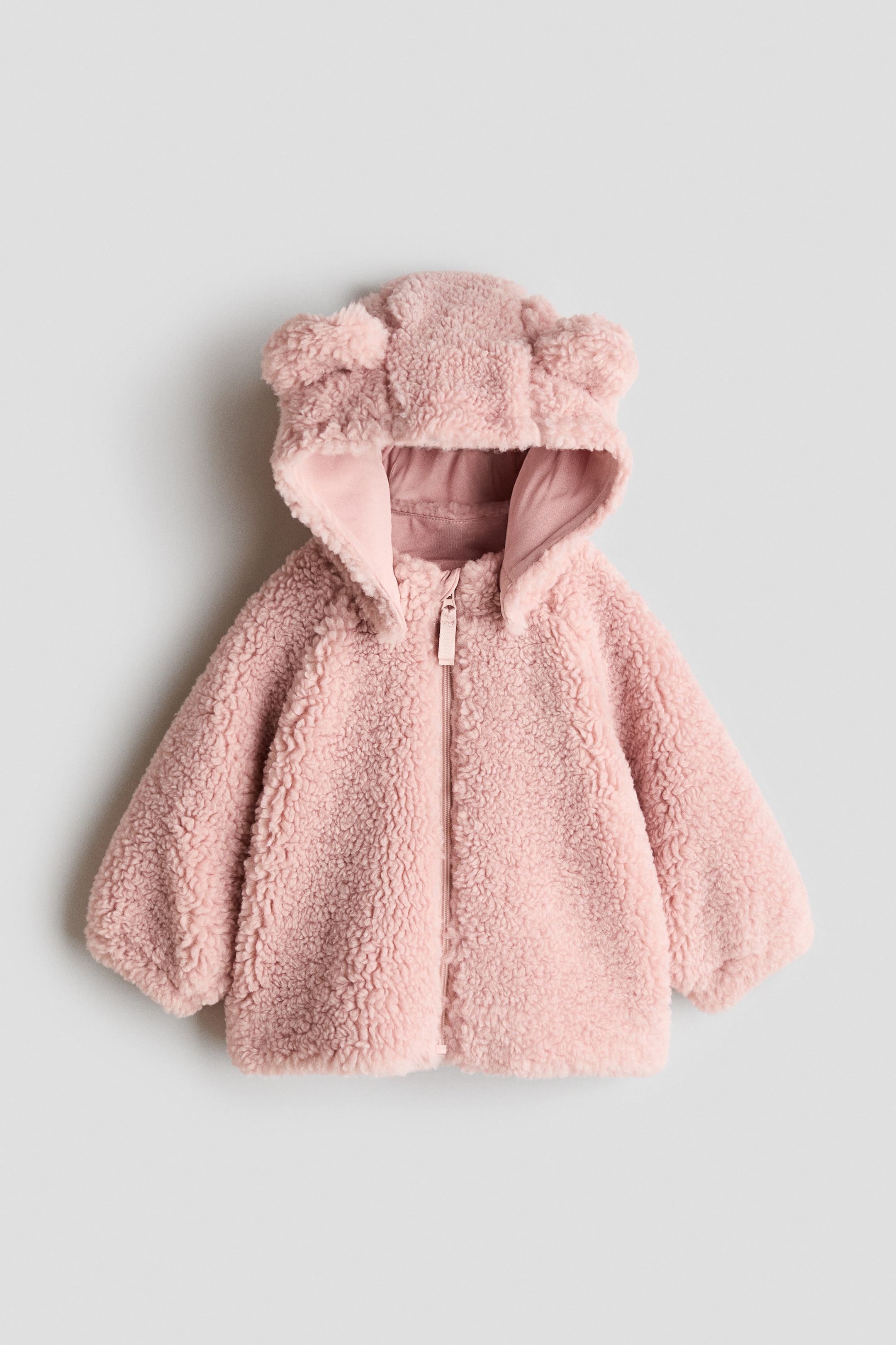View larger image: A pink sherpa jacket is shown from the front, showcasing a full-length zip closure and a hood with two small, rounded ears. The interior of the hood features a smooth, lighter pink lining.