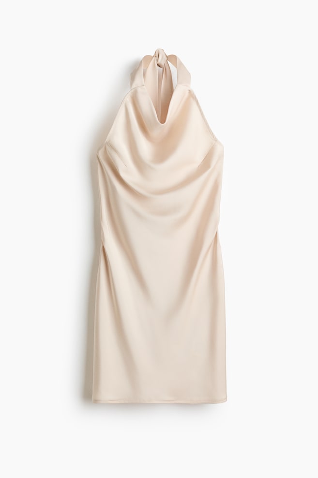 Un vestido corto de satén con una caída suave se presenta desde el frente, con un escote drapeado y anchas tiras de cuello halter que se atan en la parte posterior del cuello. Un costura vertical recorre el lado izquierdo, y un sutil fruncido es visible en el lado derecho. - 1