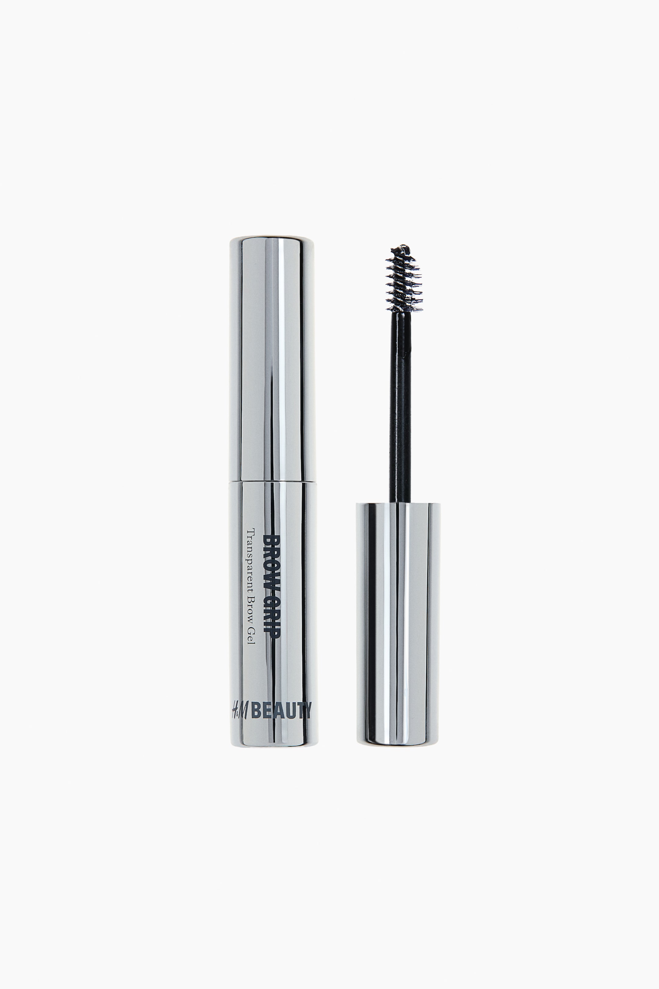 View larger image: A silver cylindrical brow gel tube stands upright, showcasing 'BROW GRIP Transparent Brow Gel' and 'H&M BEAUTY' on its front. Its detached cap and black spiral spoolie brush are positioned beside it.