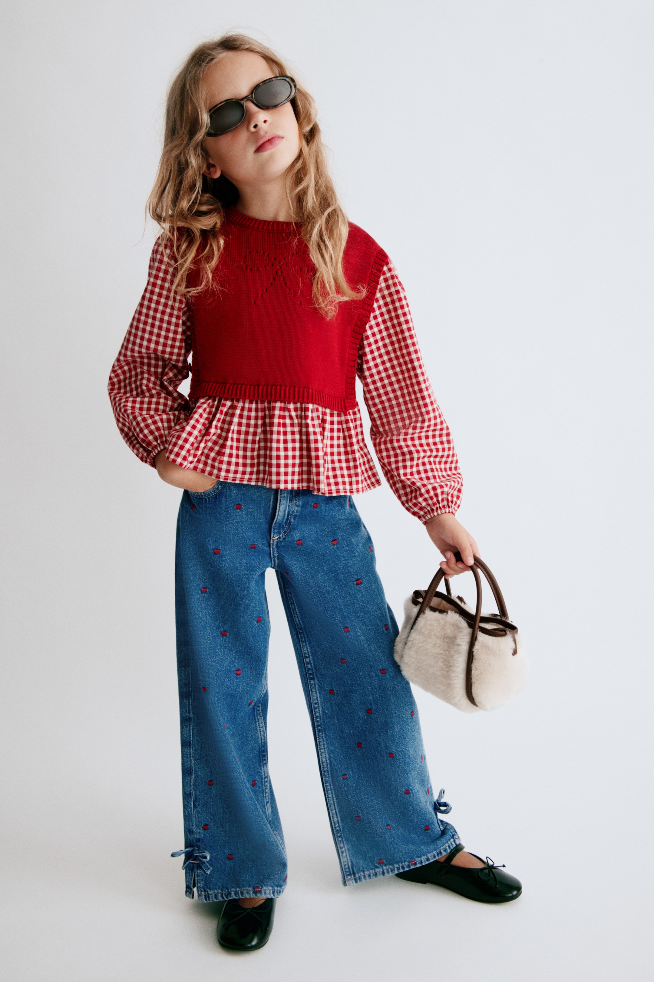 View larger image: Presenting a front view, these wide-leg blue cotton denim jeans feature a loose fit decorated with an all-over pattern of small embroidered red hearts. The design includes small side slits at the hems, detailed with self-ties.