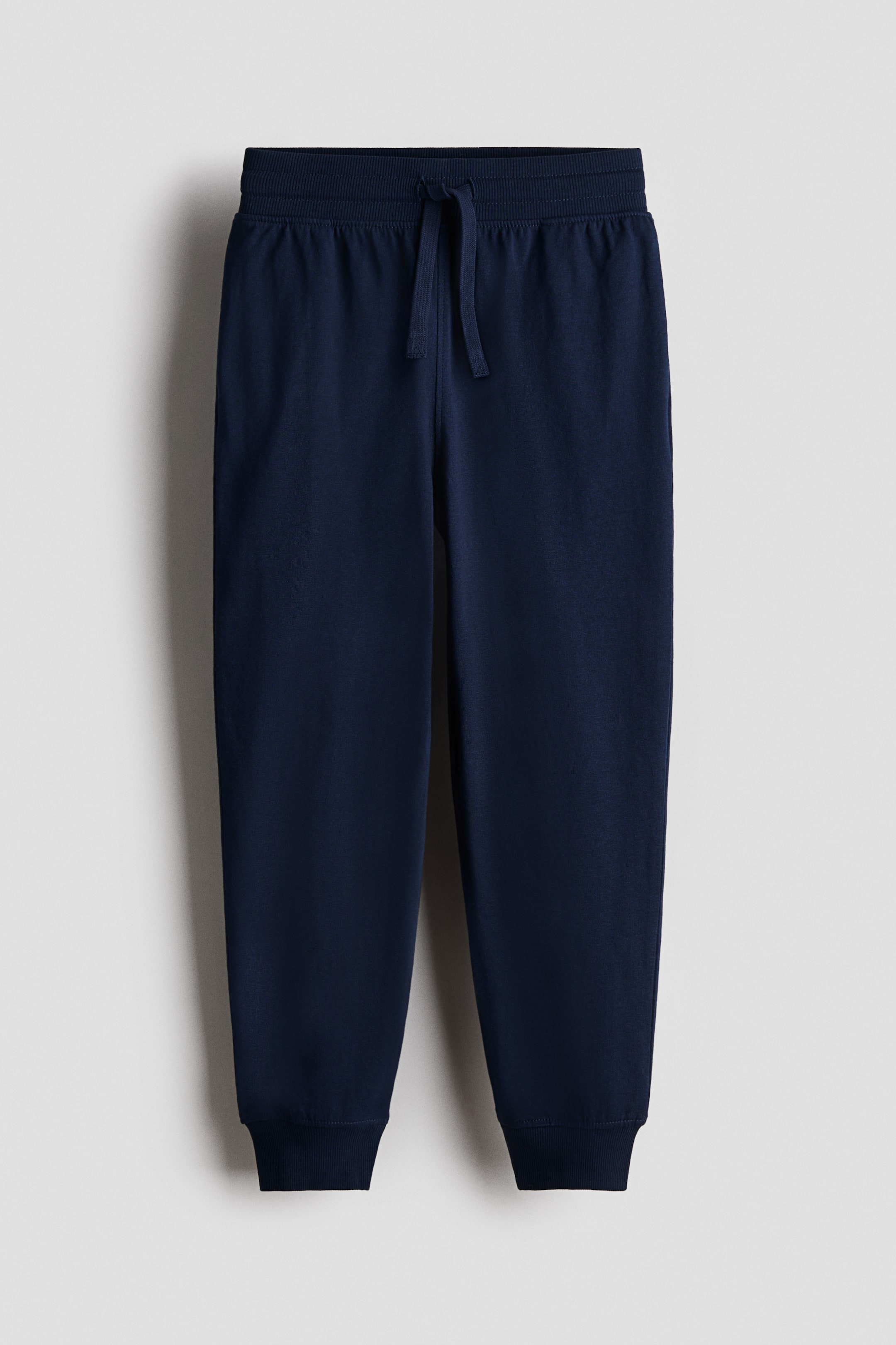 查看大圖: 深藍色 jersey joggers 以正面（FRONT）展示，配有彈性羅紋腰頭與外露束帶收口，並在腳踝處設有羅紋褲口。