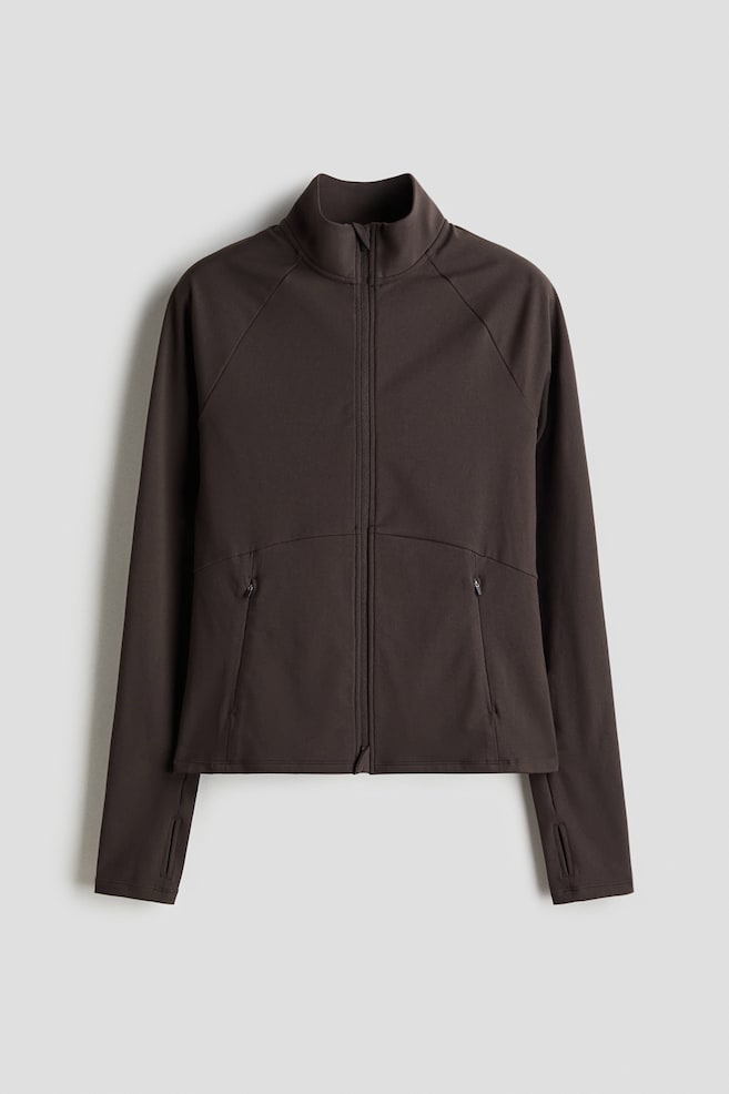 A dark brown jacket is facing front, featuring a stand-up collar, a full-zip front closure, raglan sleeves with thumbholes at the cuffs, and two angled zippered pockets on the lower front. - 1