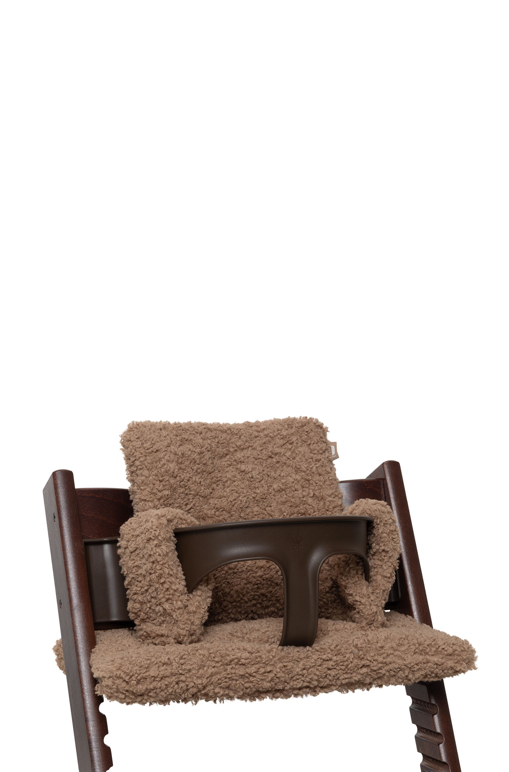 Une chaise haute en bois brun foncÃ©, Ã©quipÃ©e dâun coussin en peluche beige faÃ§on teddy fleece sur lâassise et le dossier, est orientÃ©e vers une table Ã  manger en bois.