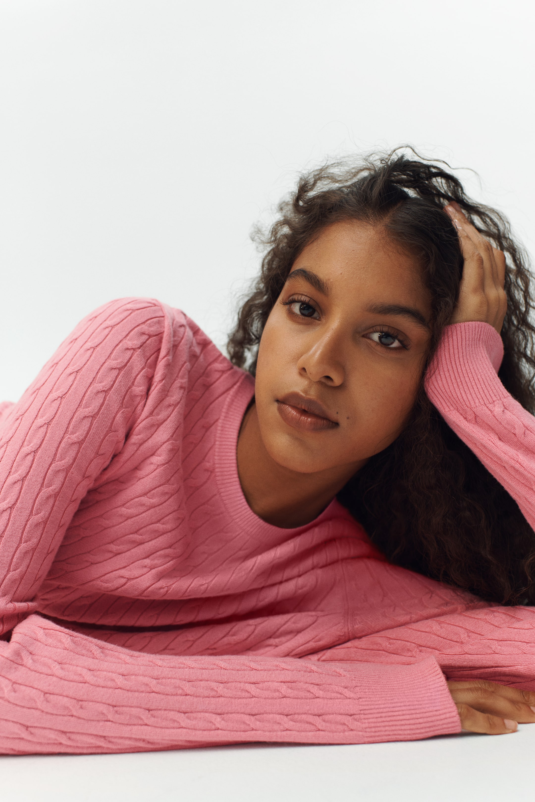 Grösseres Bild ansehen: Ein rosafarbener Zopfmusterpullover mit Rundhalsausschnitt und langen Ärmeln mit gerippten Bündchen. Der Pullover zeigt ein Zopfmuster über seine sichtbare Oberfläche.