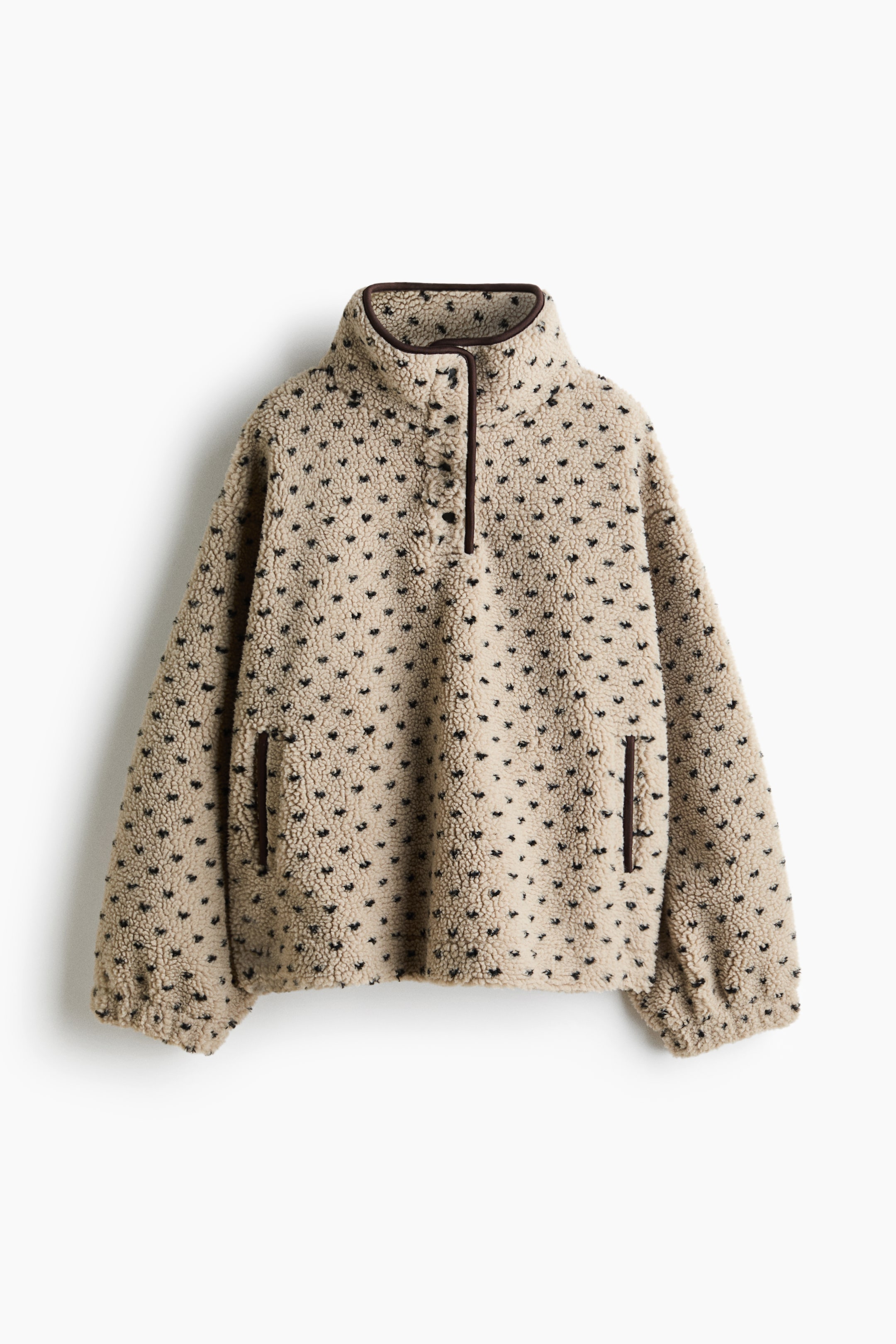View larger image: A beige teddy fleece pullover is shown facing forward, featuring an all-over pattern of small black heart-shaped dots. It is designed with a high stand-up collar and a quarter-snap placket, both trimmed with dark brown piping, and two side pockets also edged with dark brown piping.