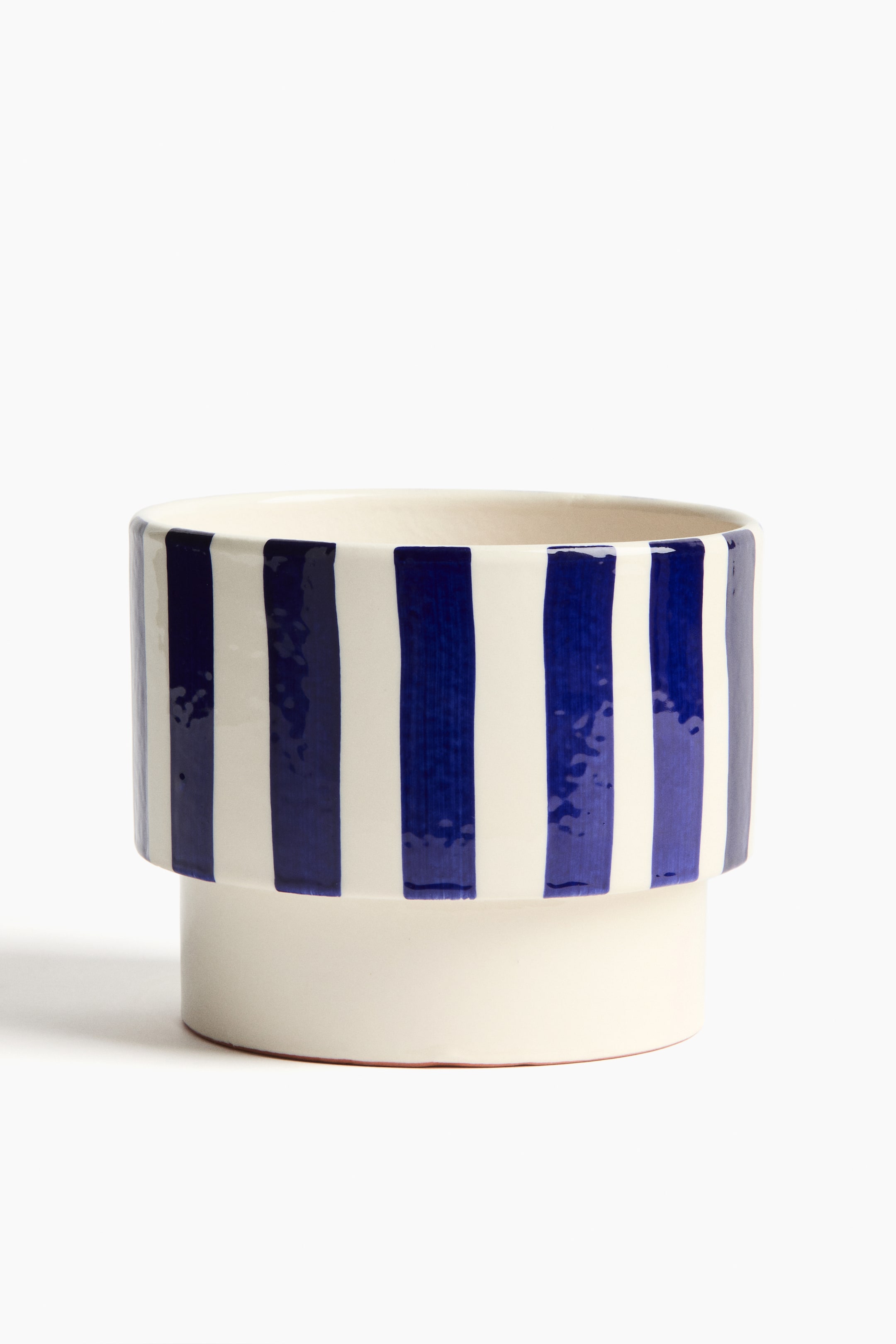 Visualizza immagine più grande: "Un vaso per piante presenta una smaltatura reattiva su terracotta smaltata, con strisce verticali variegate in blu e crema nella sua sezione superiore più ampia, che poggia su una base più stretta e semplice di colore crema."