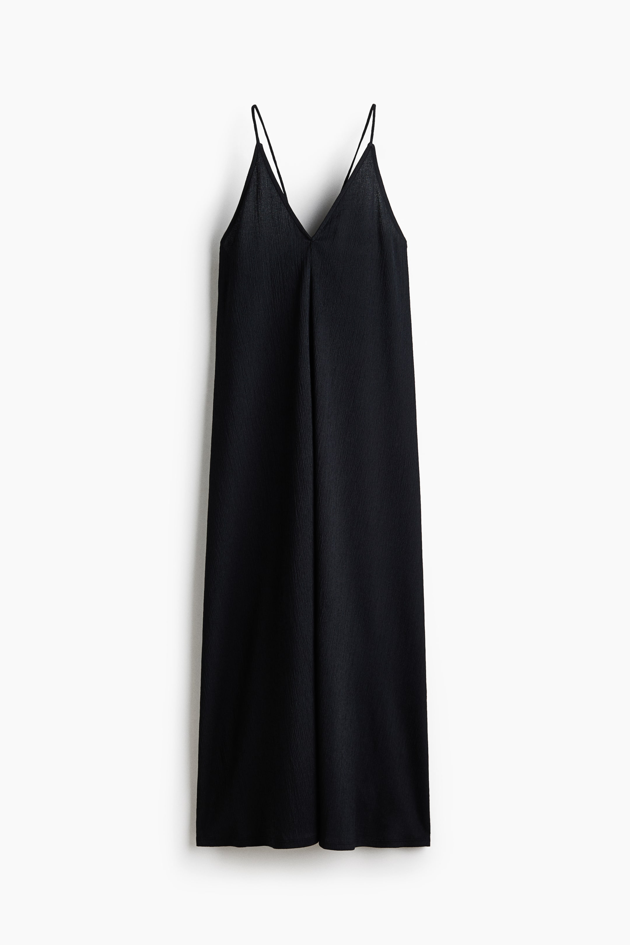 Voir une image plus grande: Une robe nuisette noire présente un décolleté en V à l'avant et de fines bretelles spaghetti doubles. Elle arbore un tissu subtilement texturé et une silhouette ample, fluide et pleine longueur.