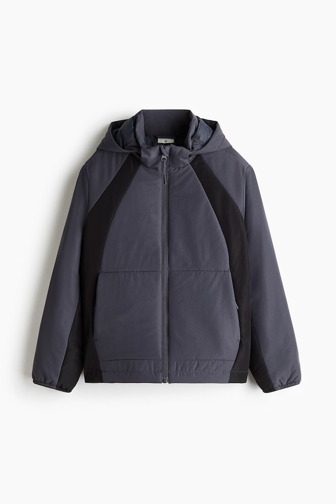 A dark grey hooded jacket is shown from the front, featuring contrasting black colour-blocked panels along the sides and underarms. The jacket is designed with a full-length front zip, integrated side pockets, and elasticated cuffs and hem. - 1