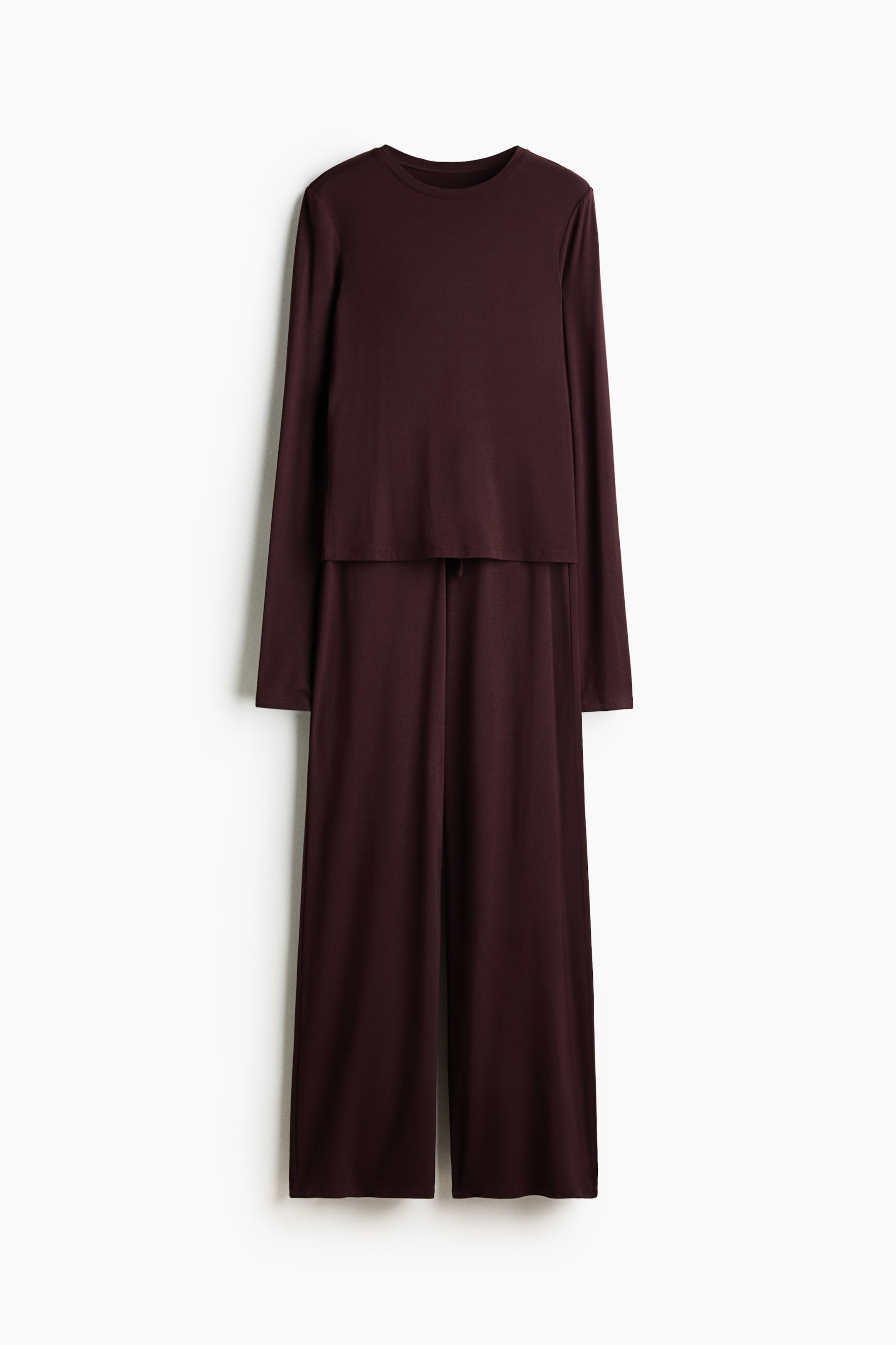 Grotere afbeelding bekijken: Een diepbordeauxkleurige tweedelige set wordt van voren gepresenteerd, met een lang mouwloze top met ronde hals die over wijde broekspijpen gaat, waarbij een zichtbare trekkoord in de taille te zien is.