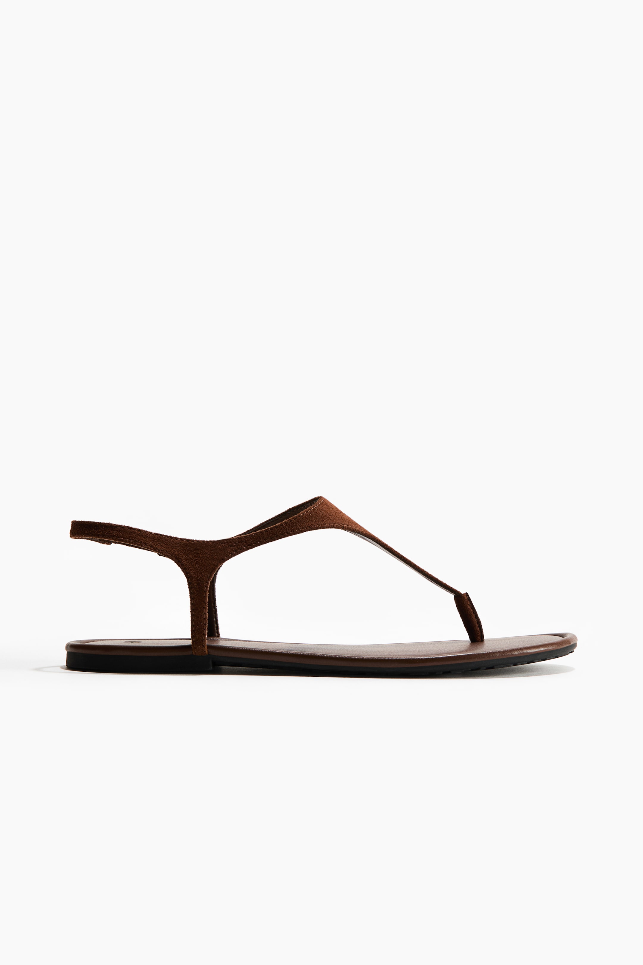 View larger image: A brown suede thong sandal features a flat, dark sole and thin straps, with a slender strap extending from the toe post across the instep to connect to an adjustable ankle strap.