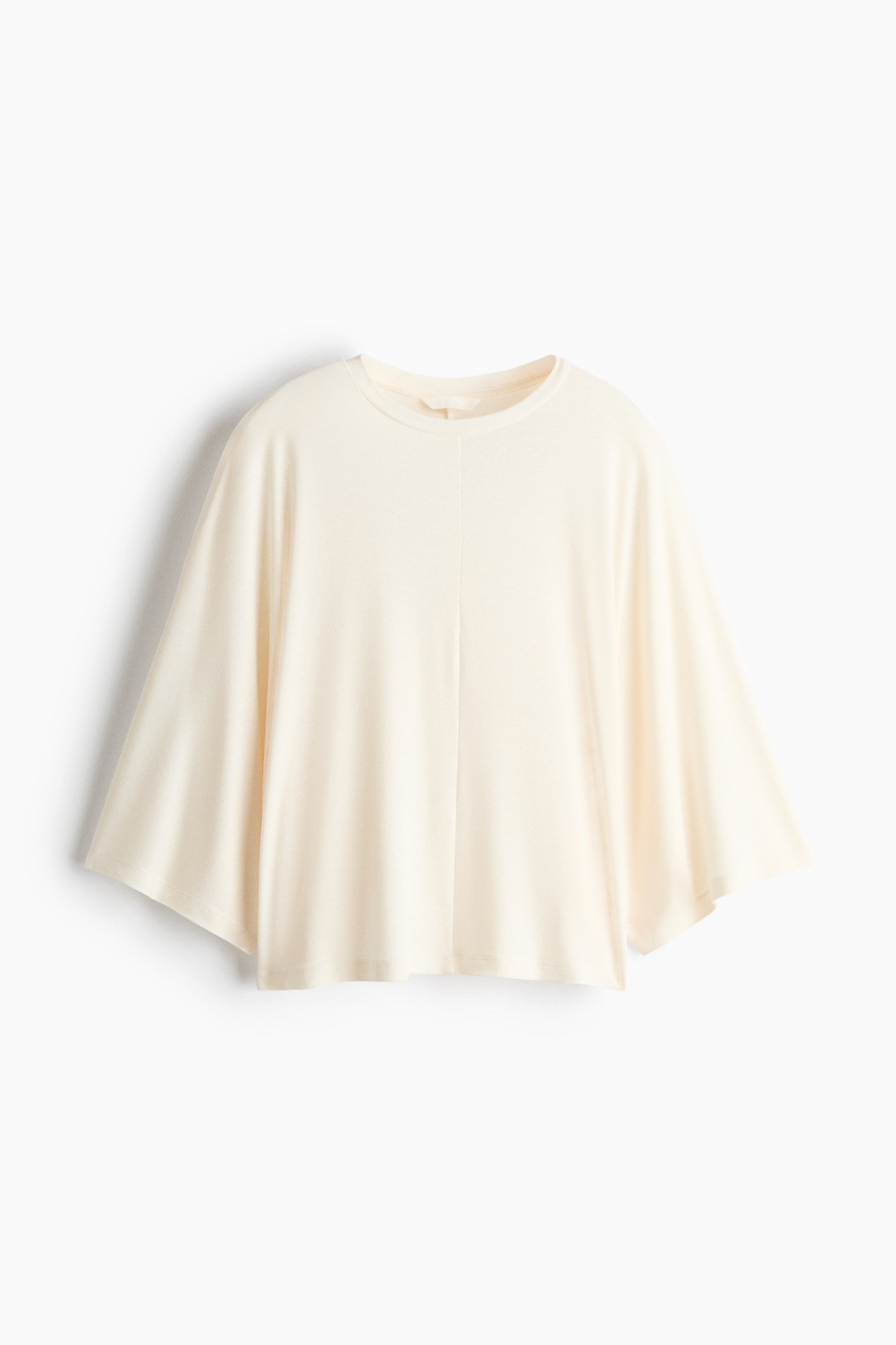 View larger image: This cream top showcases a round neckline, short dolman sleeves, and a loose, flowing fit. A vertical seam runs down the center front.