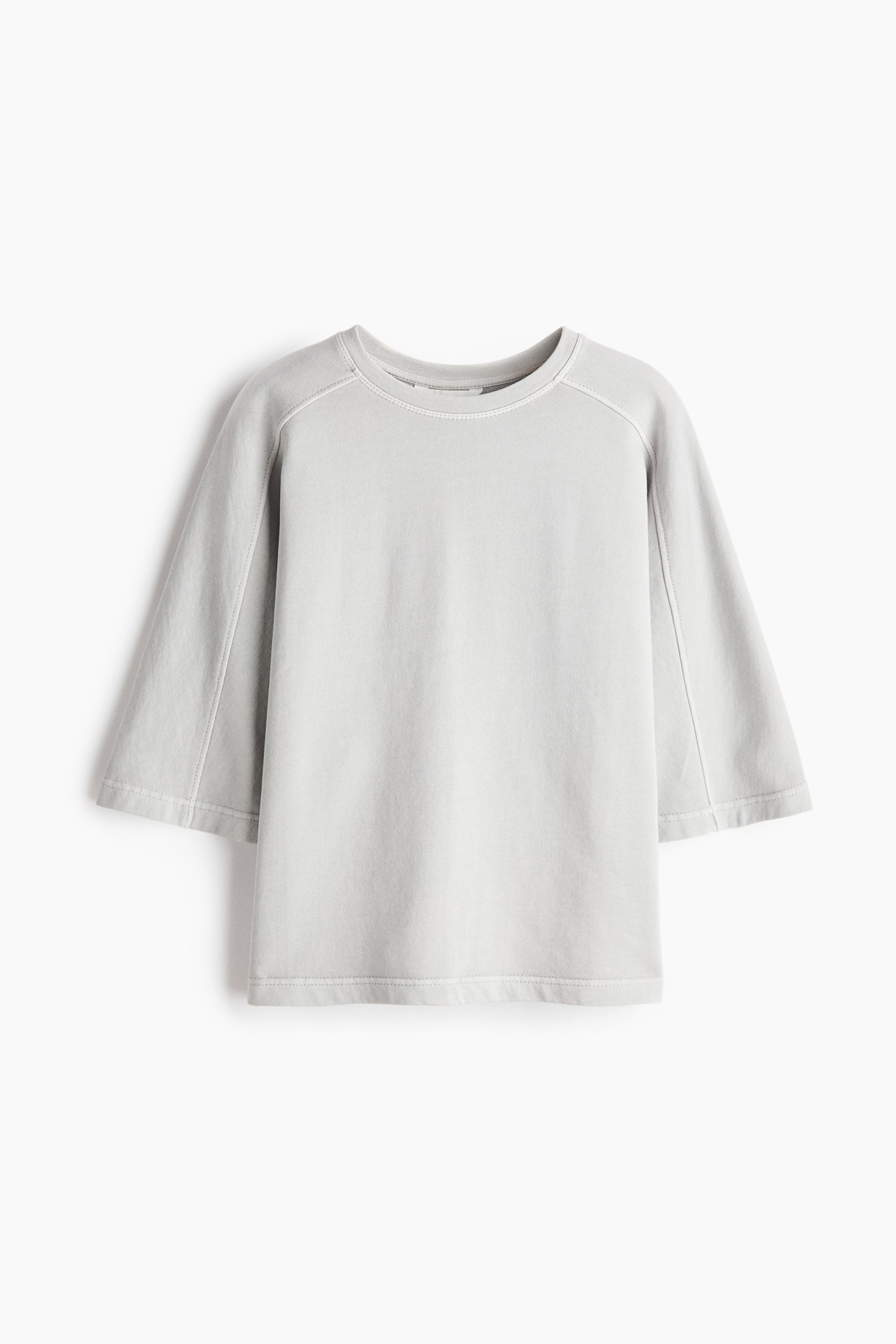 הצגת תמונה גדולה יותר: חולצה אפורה בהירה בגזרה רפויה מוצגת מלפנים, עם צווארון עגול, שרוולים רחבים באורך 3/4 עם תפירה גלויה ושוליים ישרים. עשויה מבד סווטשירט כותנה קל משקל.