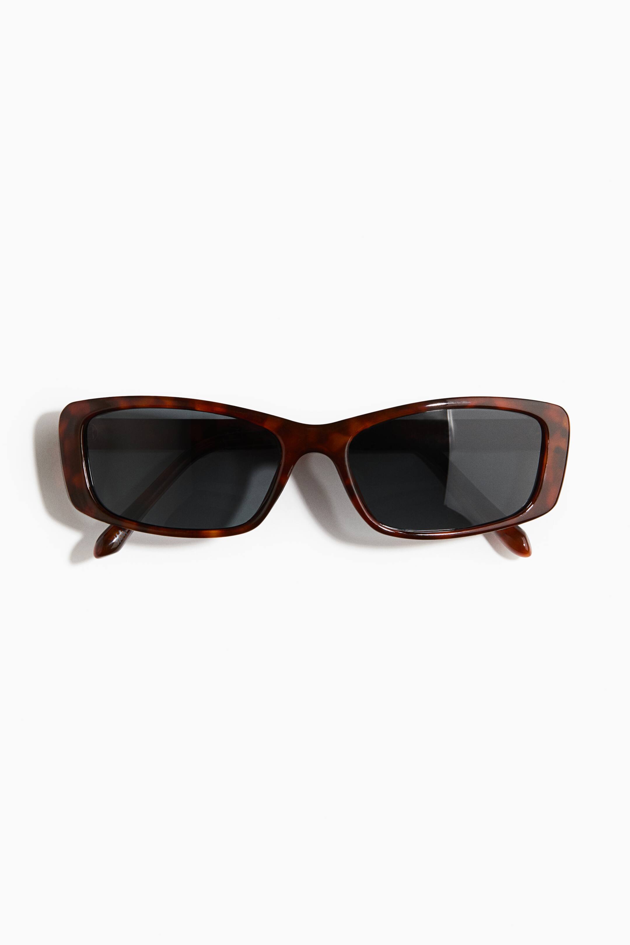 Größeres Bild ansehen: Quadratische Sonnenbrille mit Kunststoffrahmen in Schildpattoptik und dunklen Gläsern liegt flach, frontal ausgerichtet, um die rechteckige Form und die eingeklappten Bügel zu zeigen.