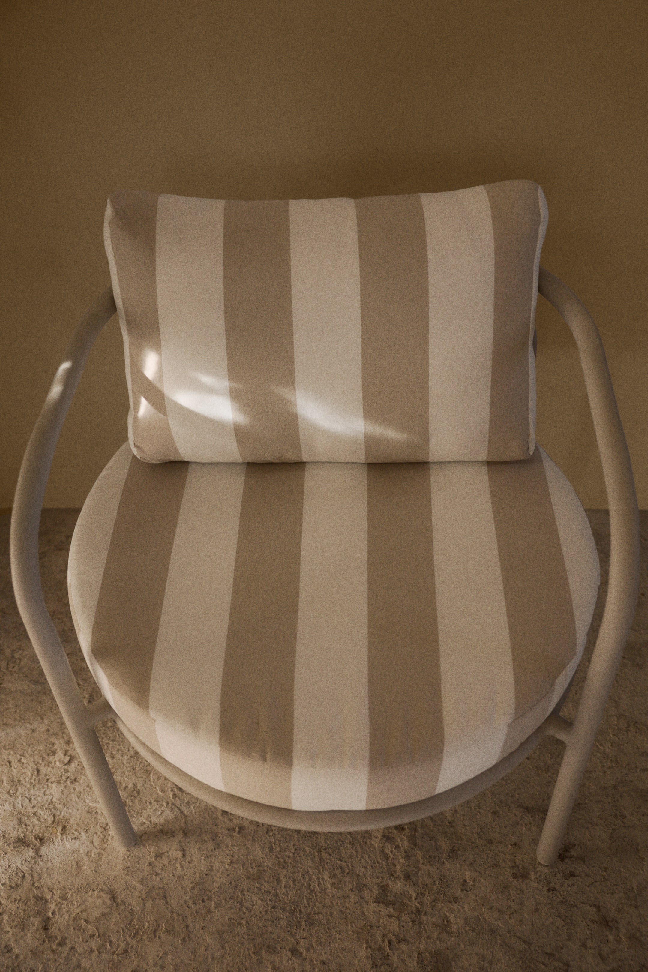 Se større billede: Stolen ses fra oven og viser dens lyse, buede ramme. Sædepuden er rund, og ryghynden er rektangulær, begge med skiftende lodrette striber i lys beige og en mørkere tan.