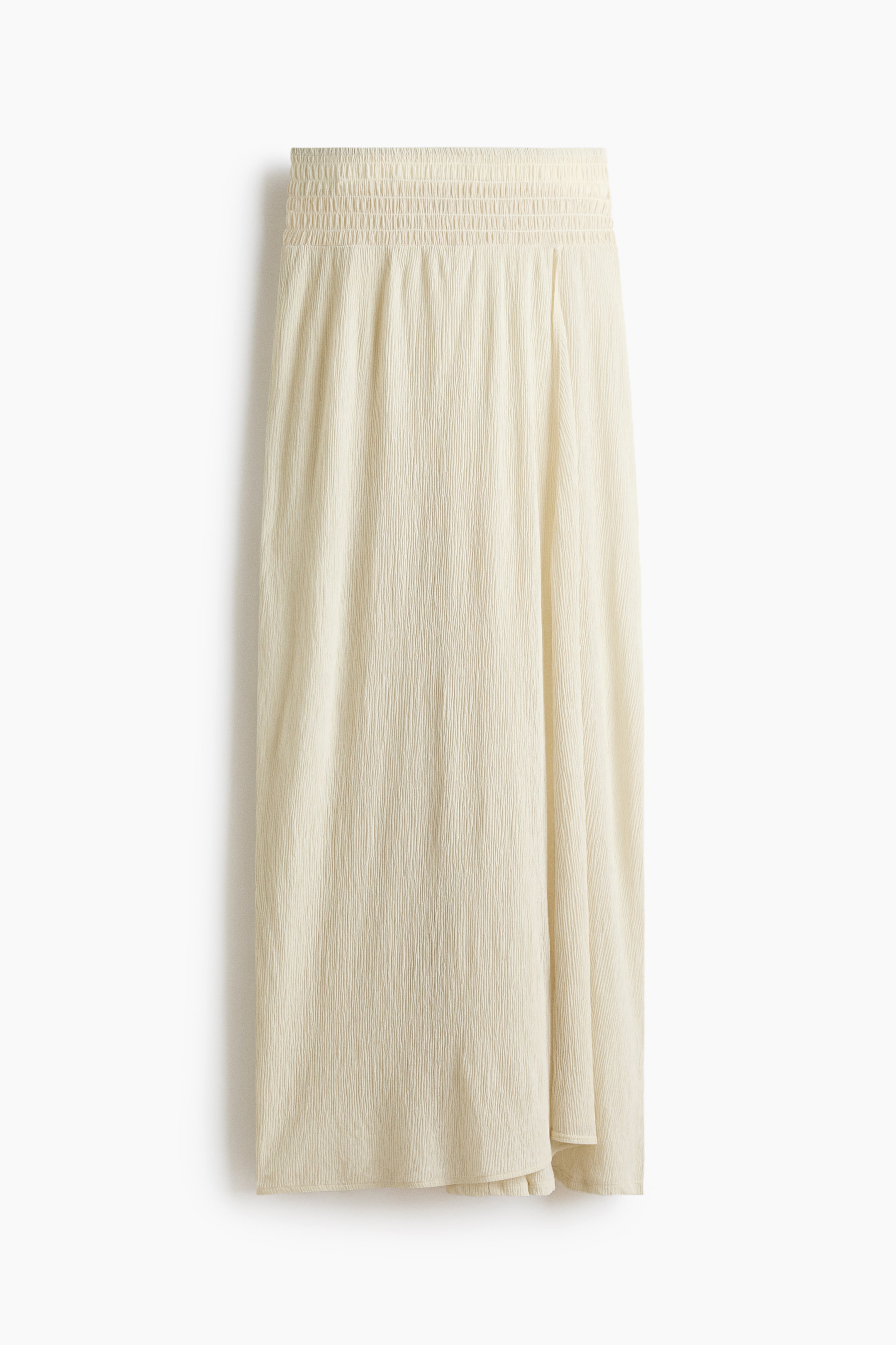 View larger image: A cream-coloured skirt is laid flat, featuring a shirred, elasticated waistband and a crinkled texture throughout the fabric.