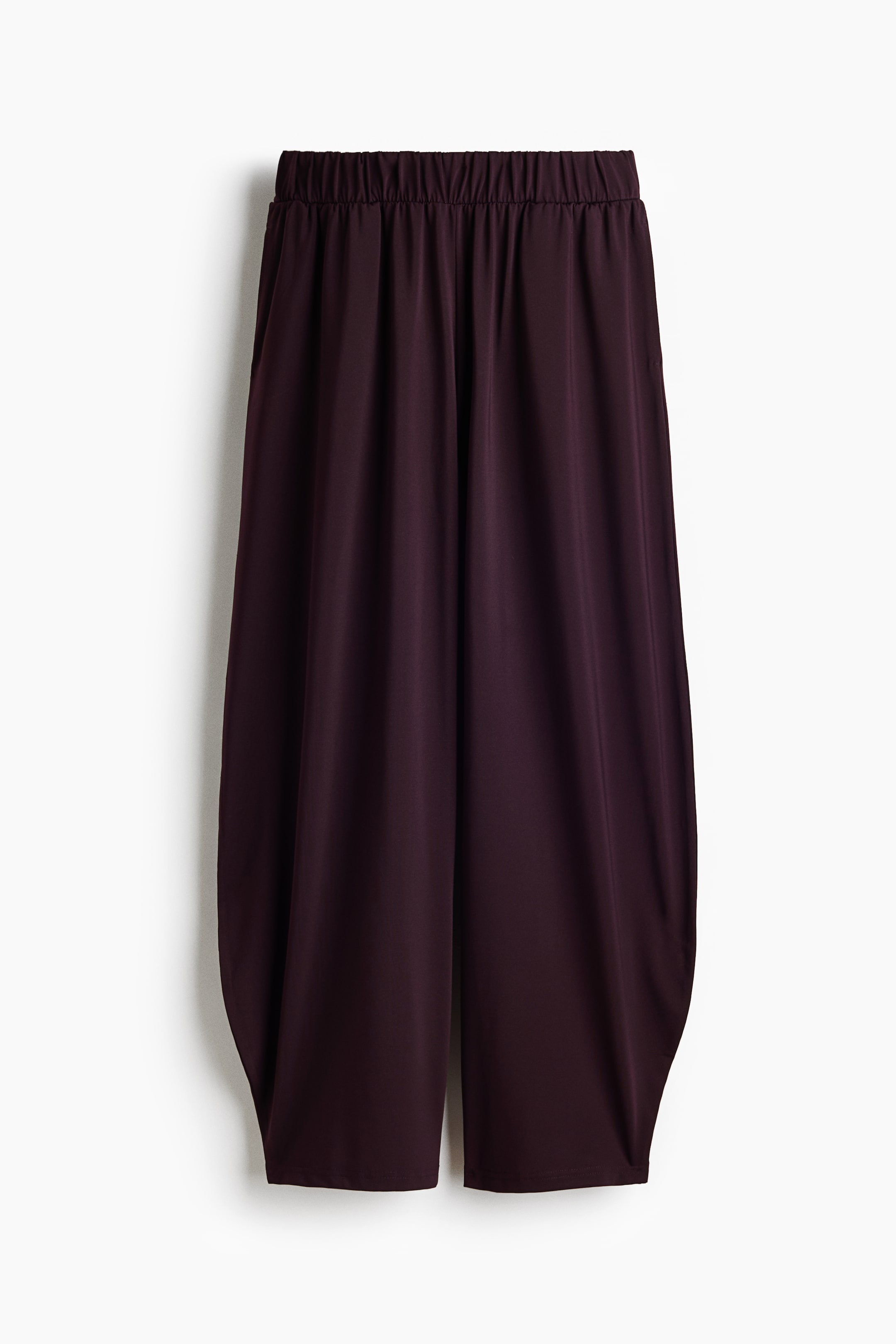 View larger image: The dark plum trousers come with an elasticated waistband and a relaxed, voluminous fit, with the legs tapering inward towards the hem.