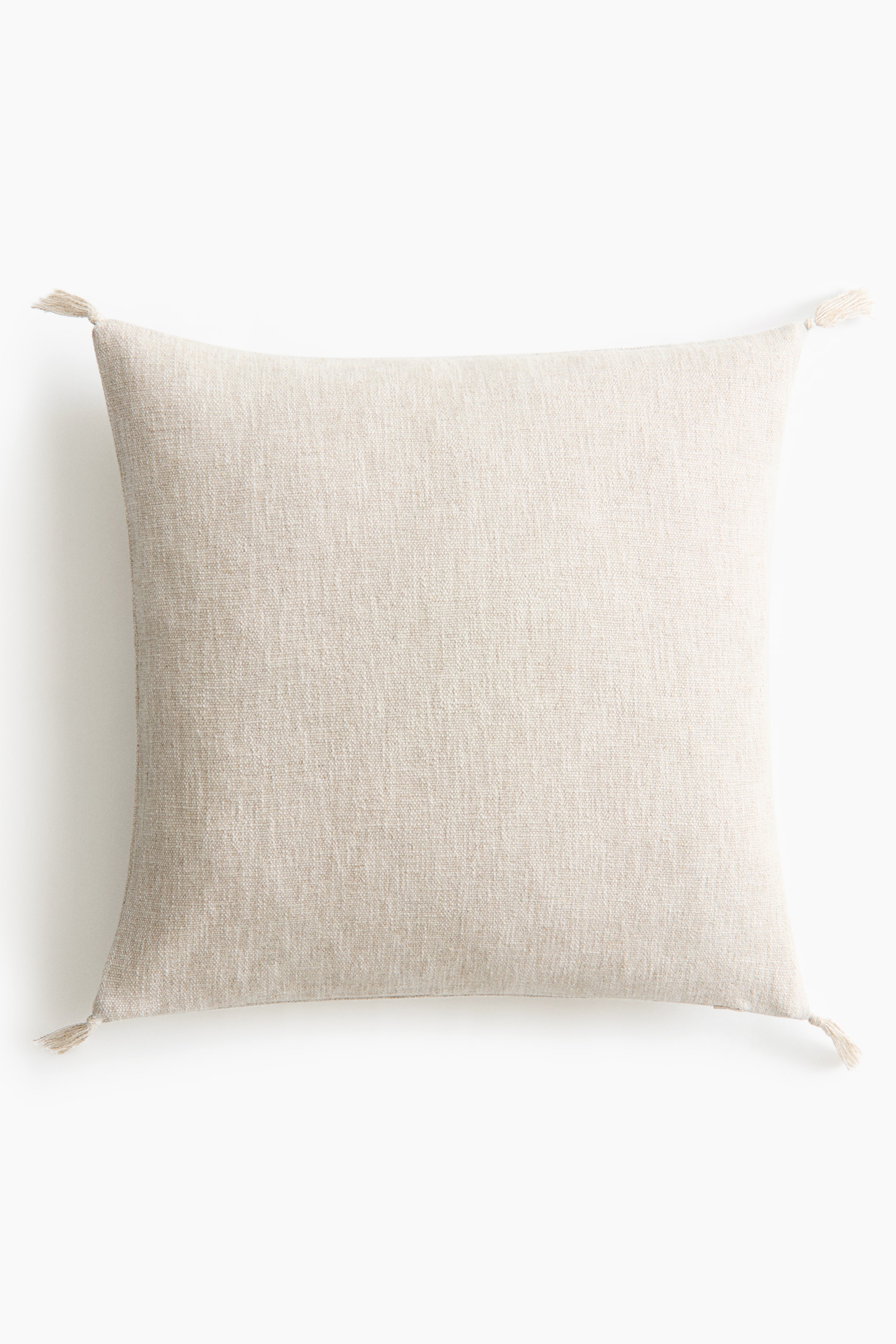 View larger image: A square throw pillow is positioned facing forward, showcasing a textured, light beige woven fabric. Small, matching tassels extend from each of the four corners.