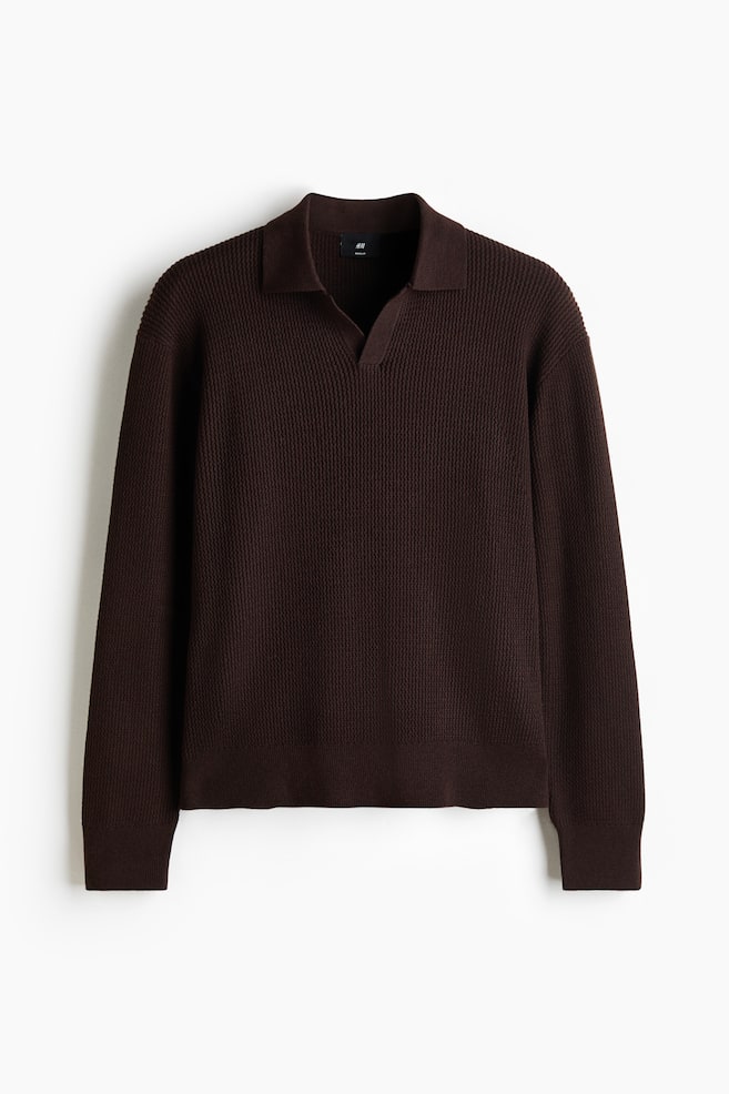 Ein dunkelbraunes Strick-Poloshirt zeigt ein strukturiertes Strickmuster. Es verfügt über einen spitzen Kragen, eine offene V-Ausschnitt-Leiste, lange Ärmel und dezent gerippte Bündchen und einen Saum. - 1