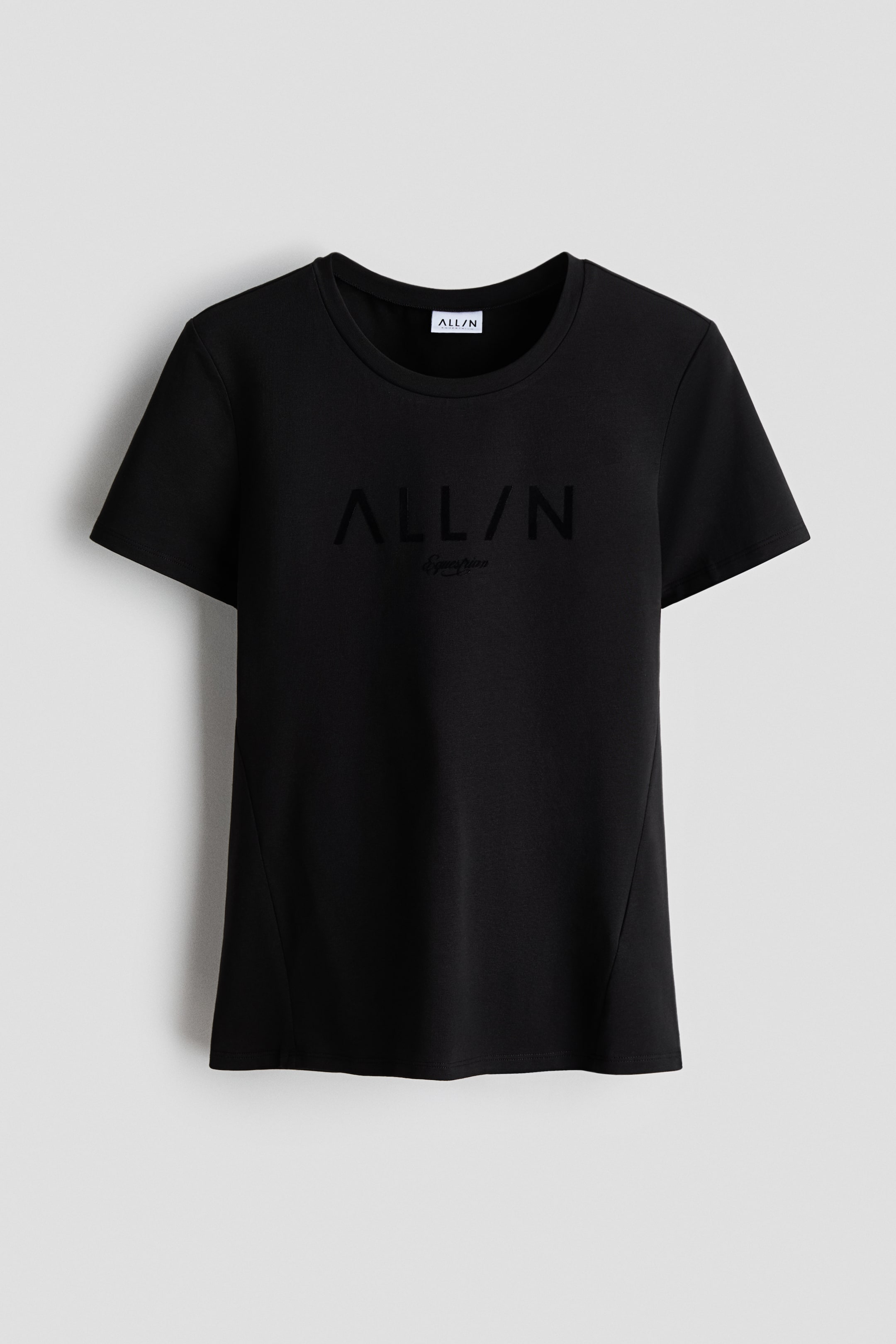 View larger image: A black T-shirt faces forward, with a crew neck and short sleeves. The front displays embossed text "ALL/N" in black, with "Everyday" in a smaller script beneath, both subtly visible against the black fabric. Angled side seams shape the silhouette, and a white "ALL/N" label is visible at the back of the neck.