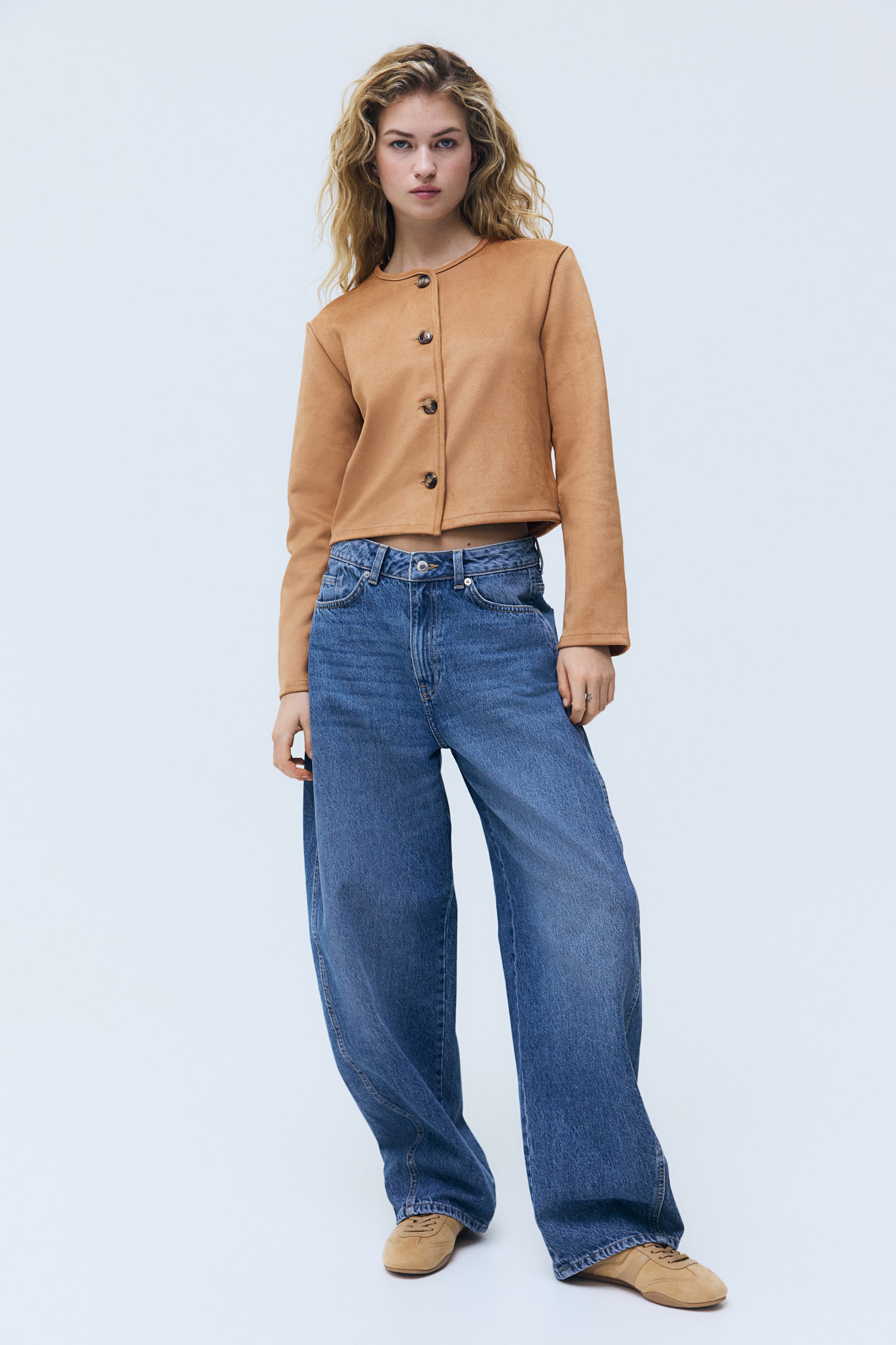 View larger image: A cropped camel-brown jacket features a round neckline and a front button closure with four dark-brown buttons. The jacket also has long sleeves and visible seam detailing on the shoulders.