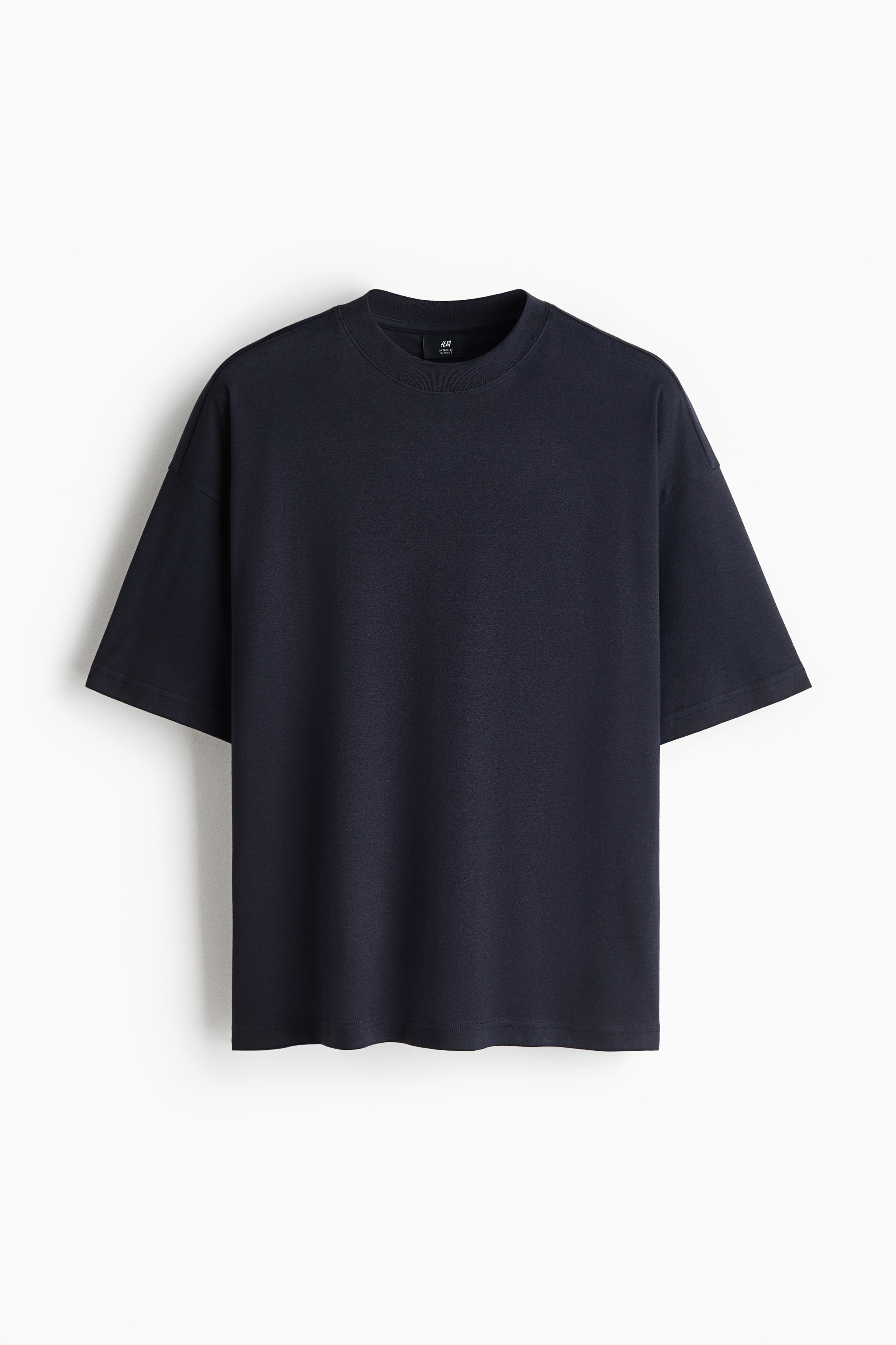 Una camiseta de cuello redondo en color gris oscuro se lleva de frente, mostrando su tela suave, ajuste relajado y mangas cortas y anchas.