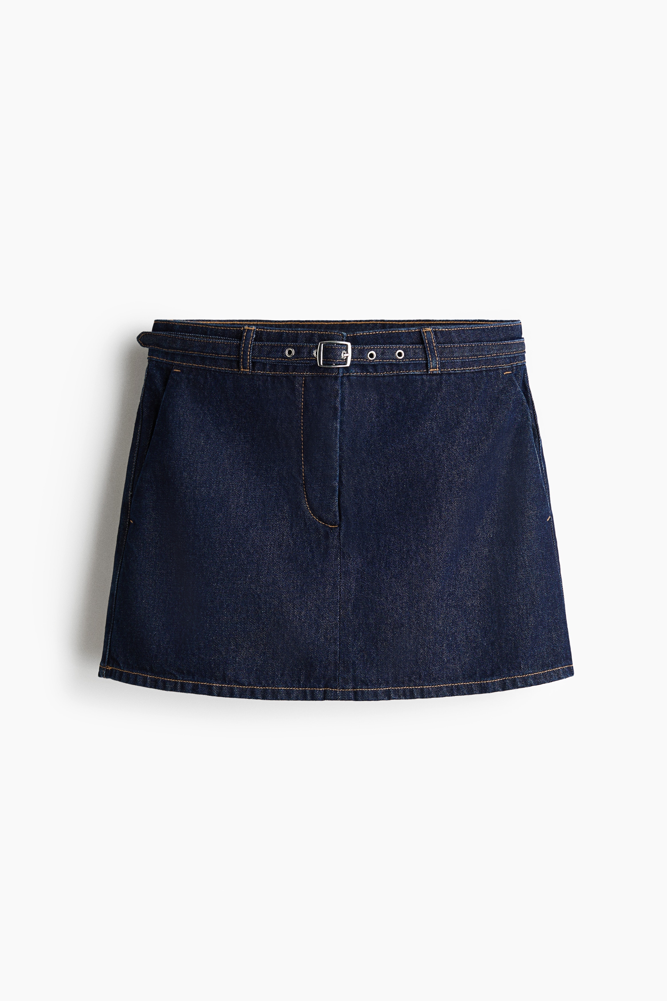 The model is wearing a short dark blue denim skirt, with one hand placed in its diagonal side pocket. The skirt is styled with a white-and-black striped short-sleeved top that drapes over the waistband.