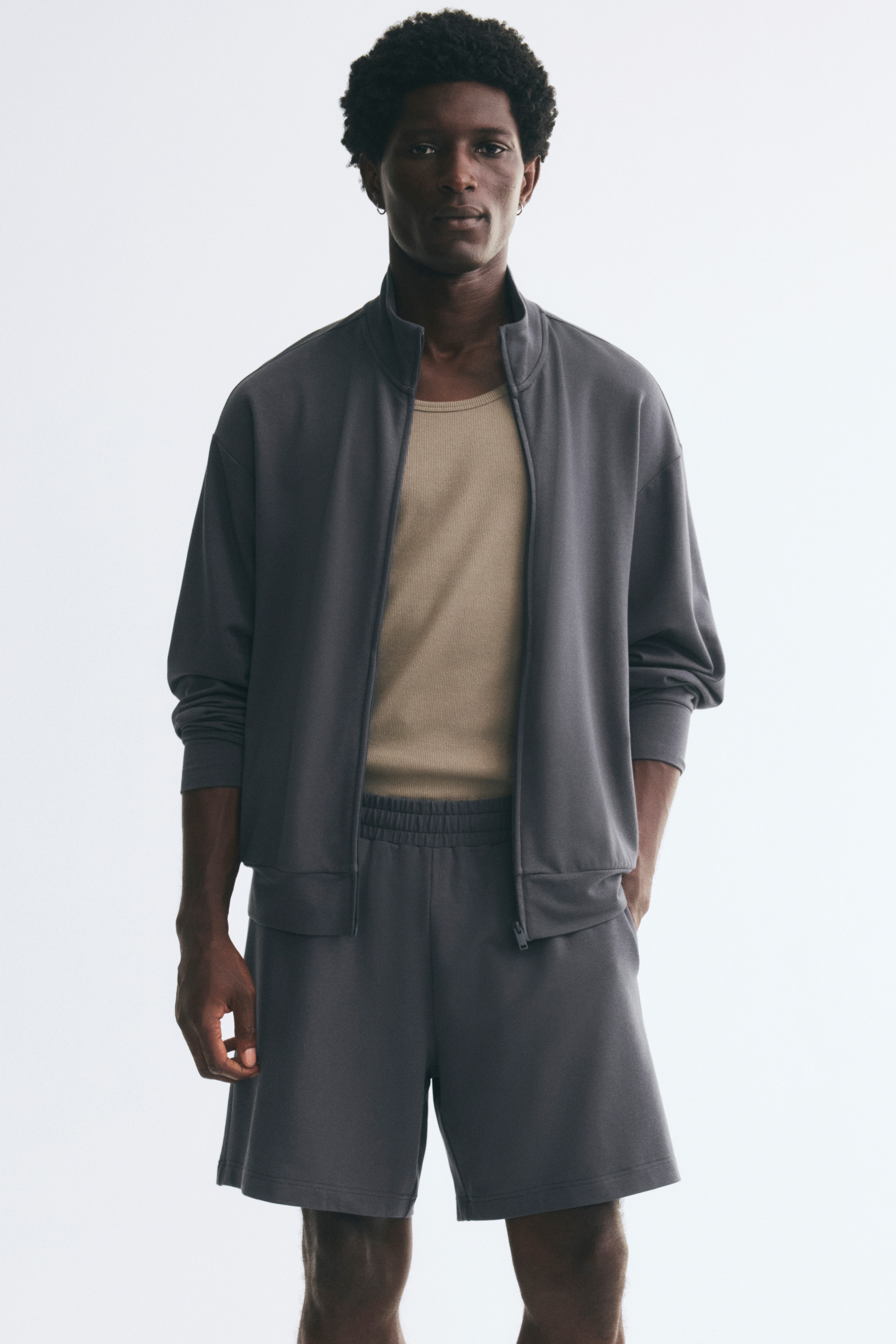 A pair of dark gray shorts is facing front, displaying a gathered elastic waistband, side-seam pockets, and stitched hems.