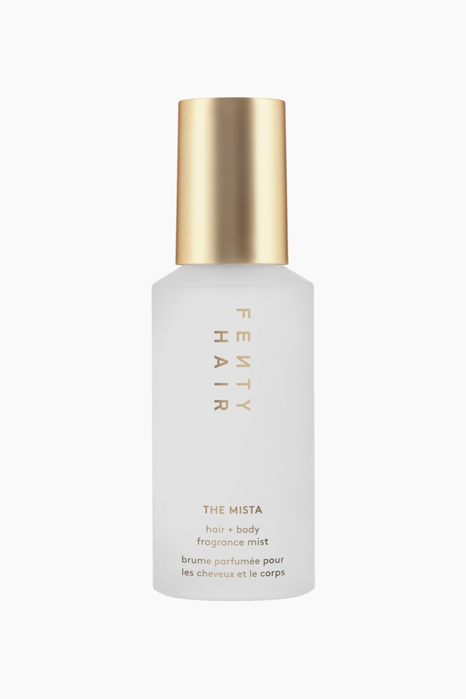 Mista Hair + Body Fragrance Mist stÃ¥r upprÃ¤tt i en framifrÃ¥n riktad vy och har en cylindrisk frostad flaska med ett metalliskt guldfÃ¤rgat lock. Framsidan av flaskan visar vertikal guldtext med "FENTY HAIR", medan "THE MISTA" och produktbeskrivningsdetaljer Ã¤r tryckta horisontellt i guld nÃ¤ra basen.