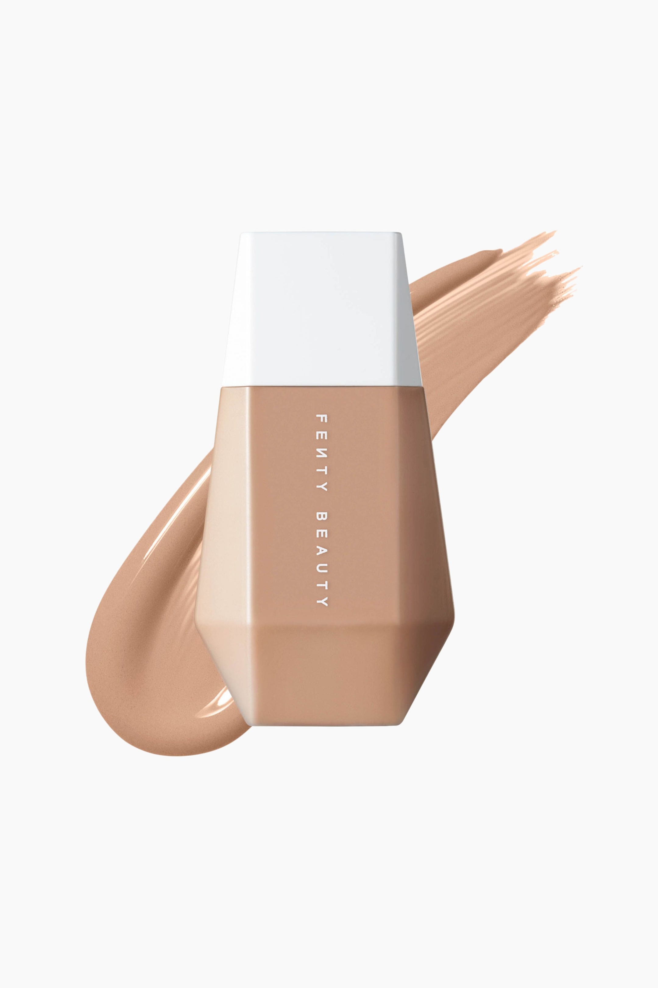 Visa större bild: En flaska Fenty Beauty Eaze Drop skin tint, i en mångfasetterad, geometrisk förpackning med vertikal vit text och ett avsmalnande vitt lock, står upprätt. En diagonal svepning av den matchande ljus-medelbeiga flytande foundationen löper bakom flaskan och lyfter fram dess lena textur.