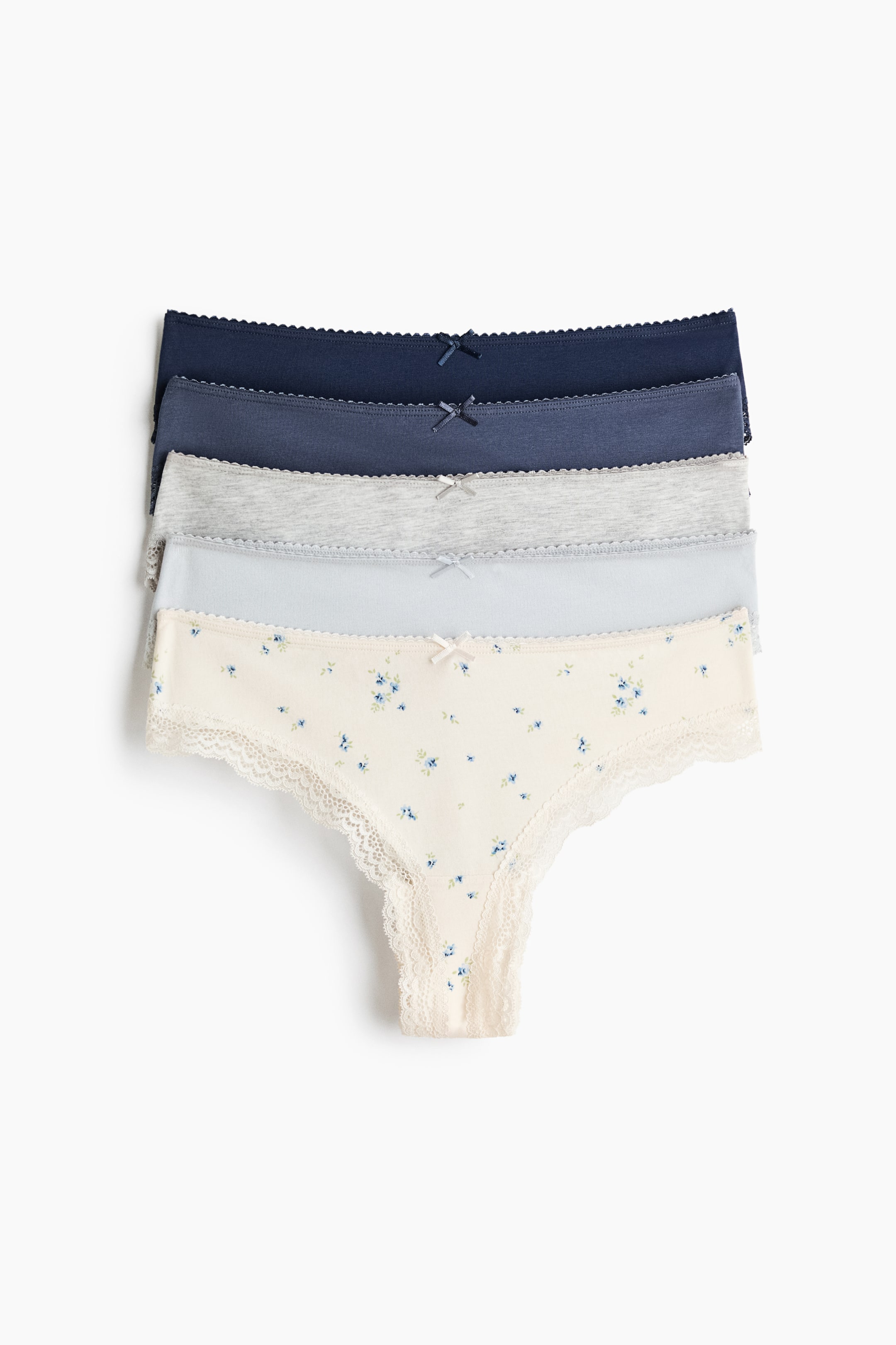 View larger image: Five Brazilian briefs are neatly stacked, showcasing shades of navy, blue, grey, light blue, and a cream floral print. Each brief features a low waist, delicate lace trims along the leg openings, and a small bow at the centre front.