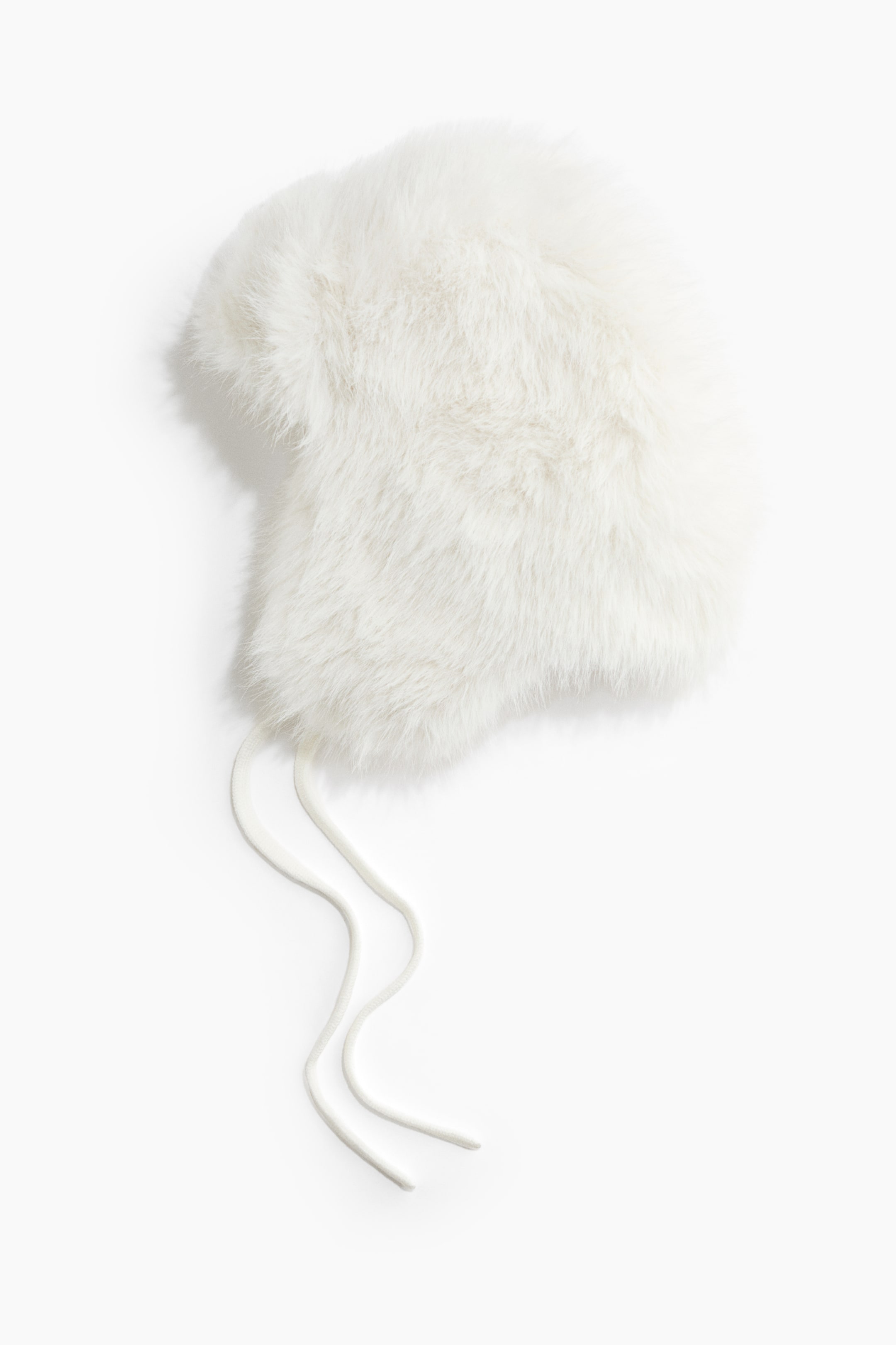 Ver imagen más grande: Un gorro trapper de pelo sintético blanco yace extendido, mostrando su textura suave y esponjosa, las orejeras y dos largos cordones tejidos blancos que cuelgan por un lado.