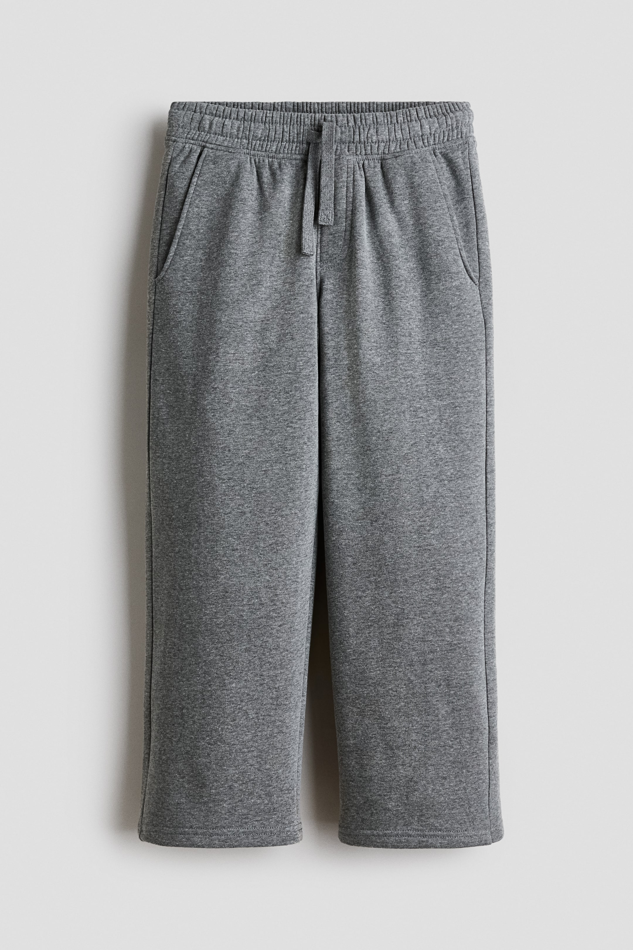 View larger image: The gray joggers are shown from the front, highlighting an elastic, drawstring waist and angled side pockets. Their wide legs are crafted from a marled gray sweatshirt fabric.