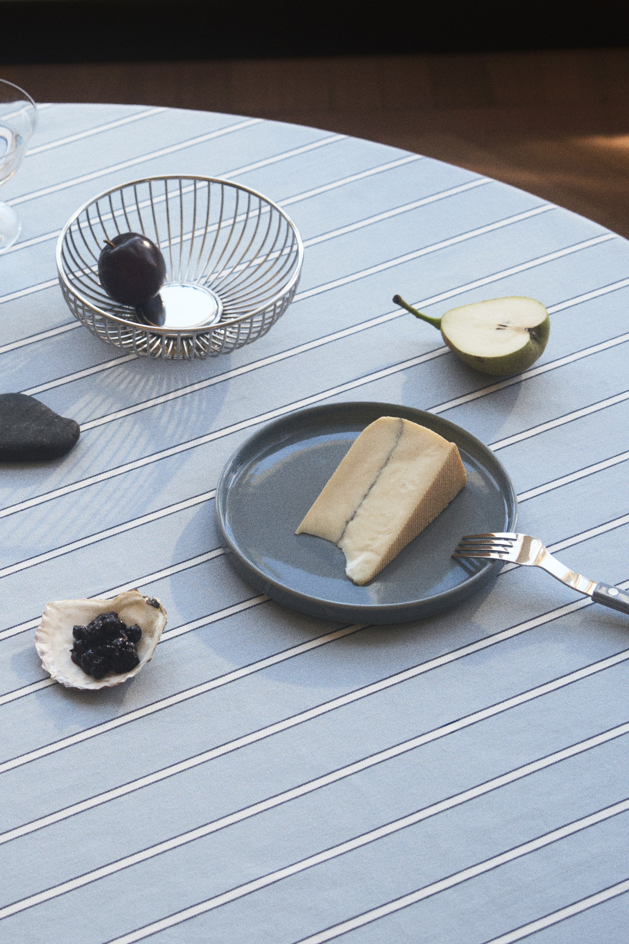 View larger image: A round, grey ceramic plate is presenting a triangular slice of cheese, with a fork resting beside it. The plate features a smooth, slightly raised rim and a uniform matte finish.