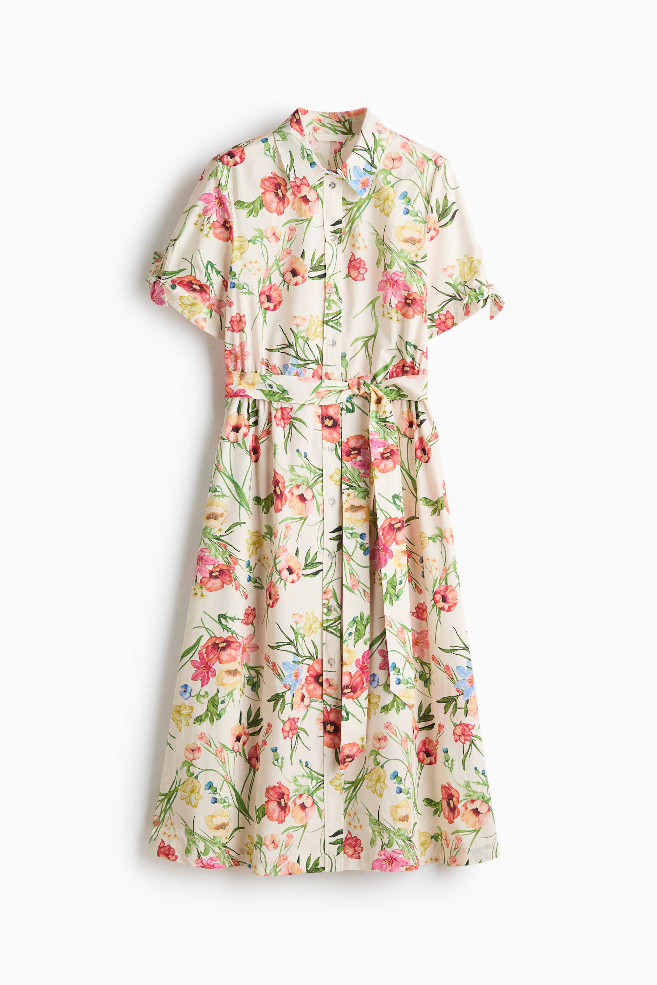 View larger image: The calf-length dress is shown from the front, showcasing a colourful floral print on a light background, a collar, buttons down the front, short sleeves with ties at the cuffs, a gathered seam at the waist, a detachable tie belt, and a gently flared skirt.
