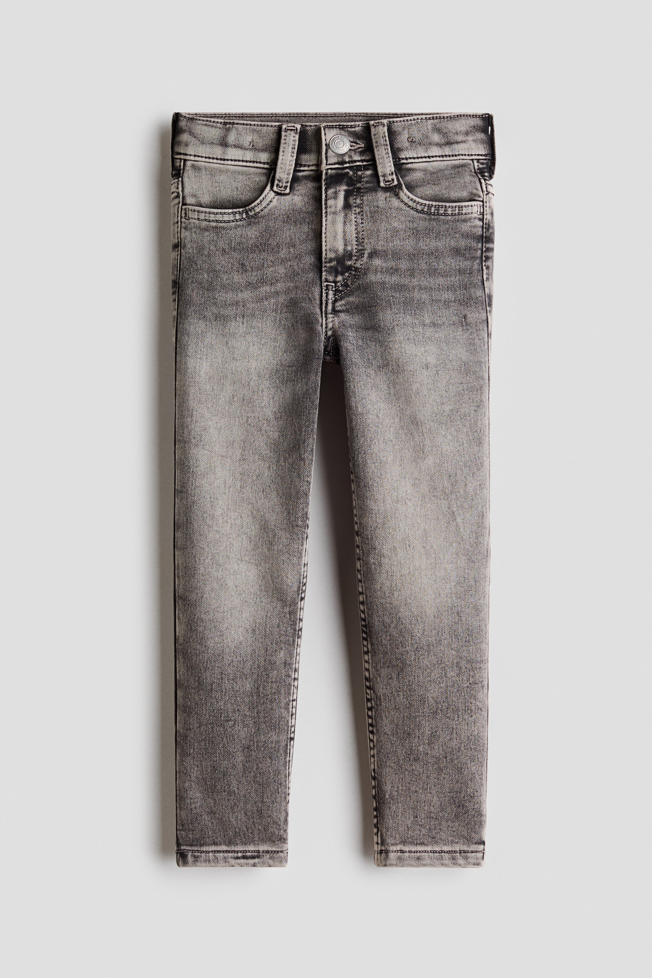 View larger image: These slim-fit jeans in a faded grey wash are laid flat in a front view, showcasing a waistband with belt loops, a single button closure, and front scoop pockets.