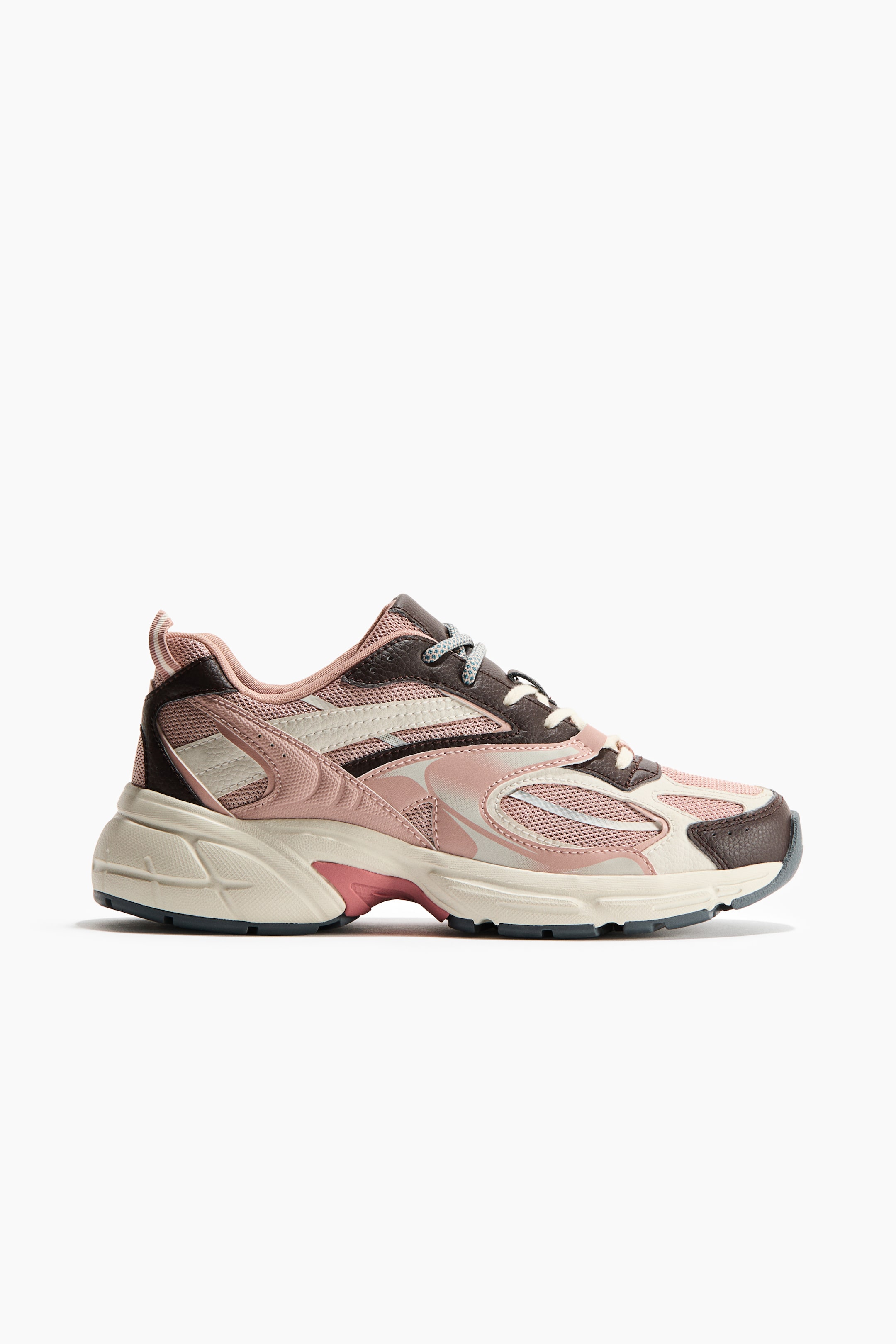Visa större bild: En sneaker är tillverkad av mesh och belagt tyg i rosa, krämfärgat och brunt, med ljusgrå snörning framtill och en rosa dragögla baktill. En tjock sula syns med en mörkgrå mönstrad undersida.
