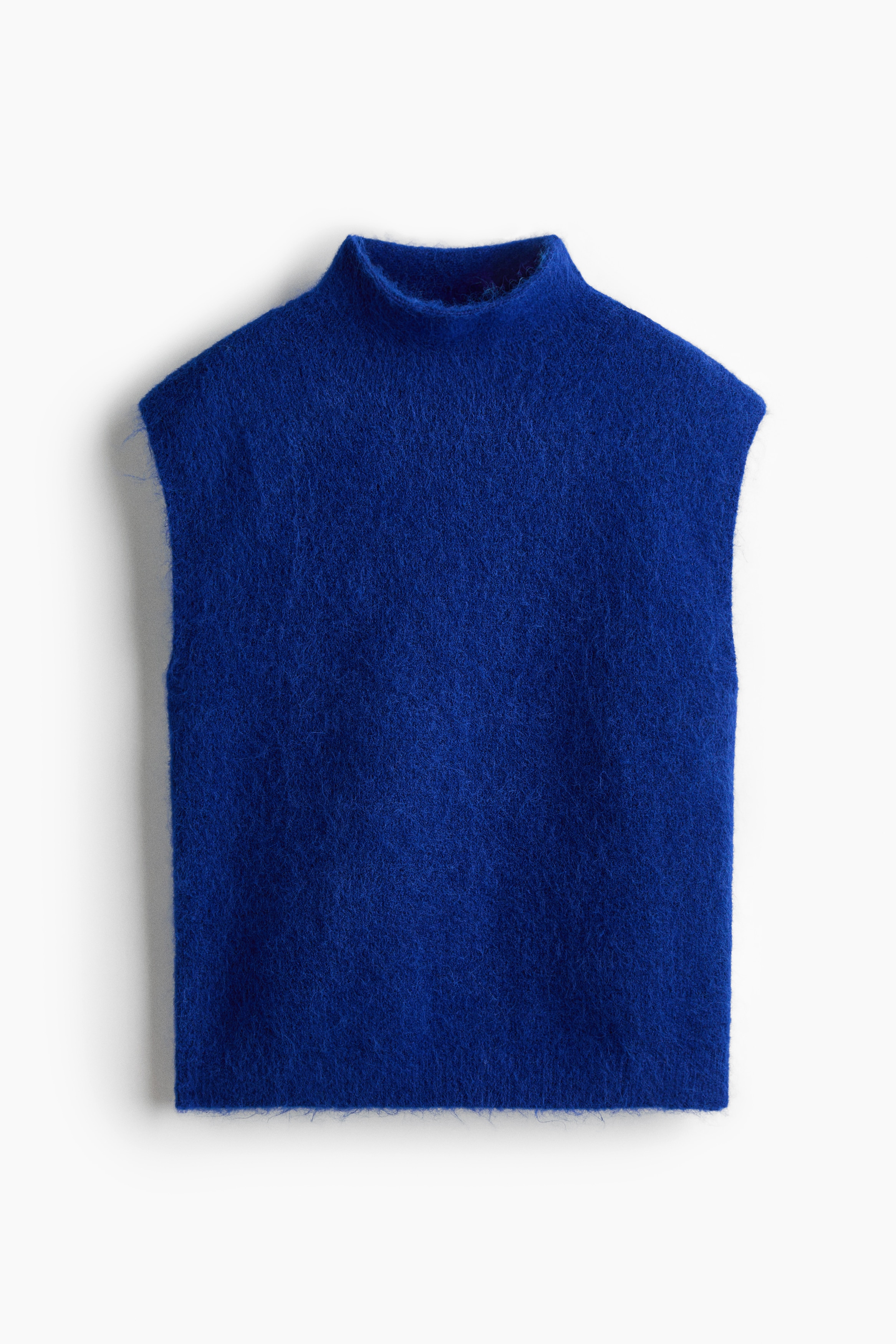 Un gilet en maille bleu vif Ã  col montant, avec une texture douce et brossÃ©e, est portÃ© par le mannequin. Ce gilet sans manches est associÃ© Ã  une chemise Ã  carreaux marron nouÃ©e Ã  la taille, portÃ©e sur un pantalon foncÃ©.