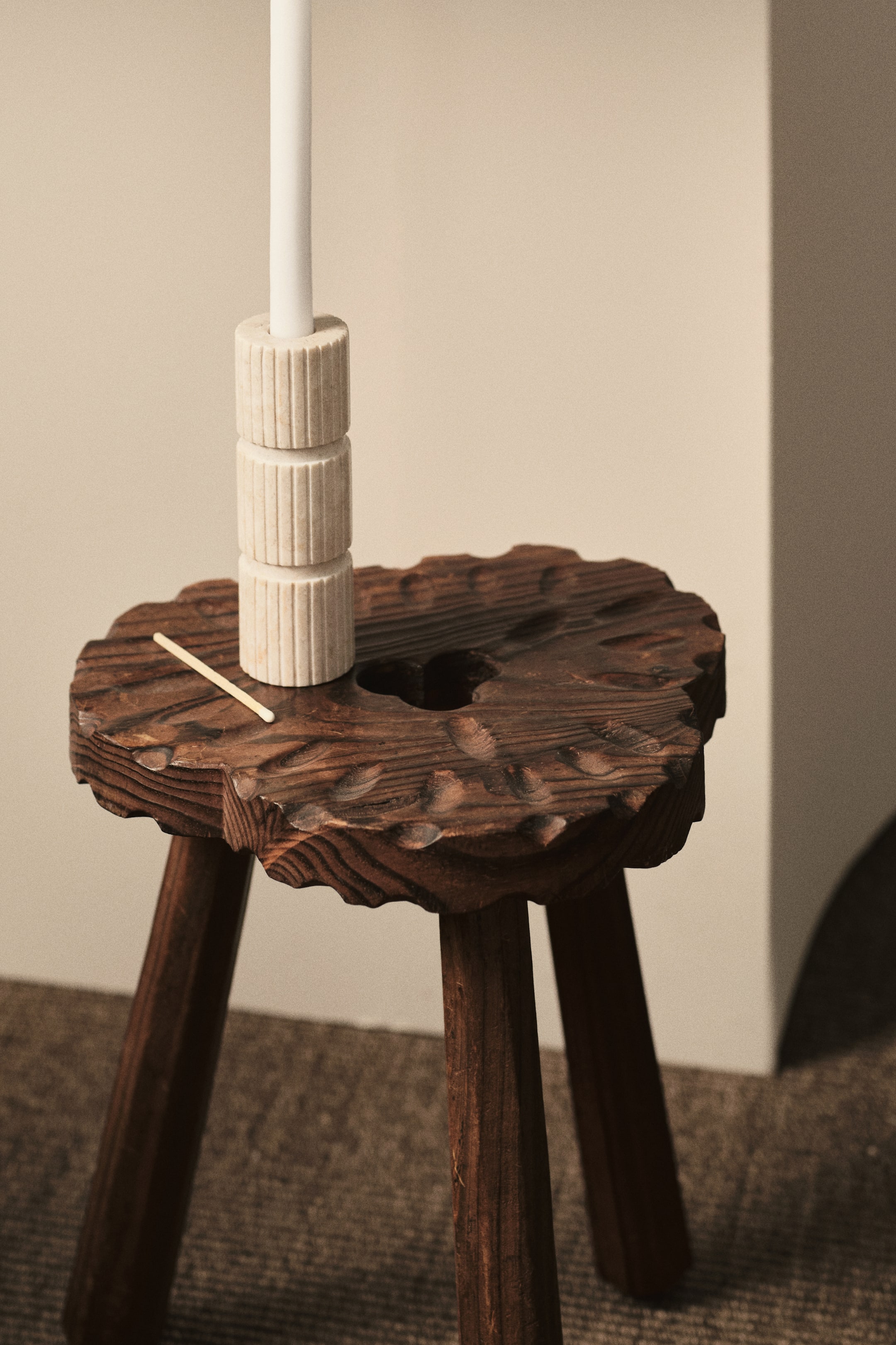 Visualizza l'immagine ingrandita: Un alto candeliere in marmo presenta un design scanalato, con i suoi tre segmenti cilindrici impilati che sorreggono una candela bianca.