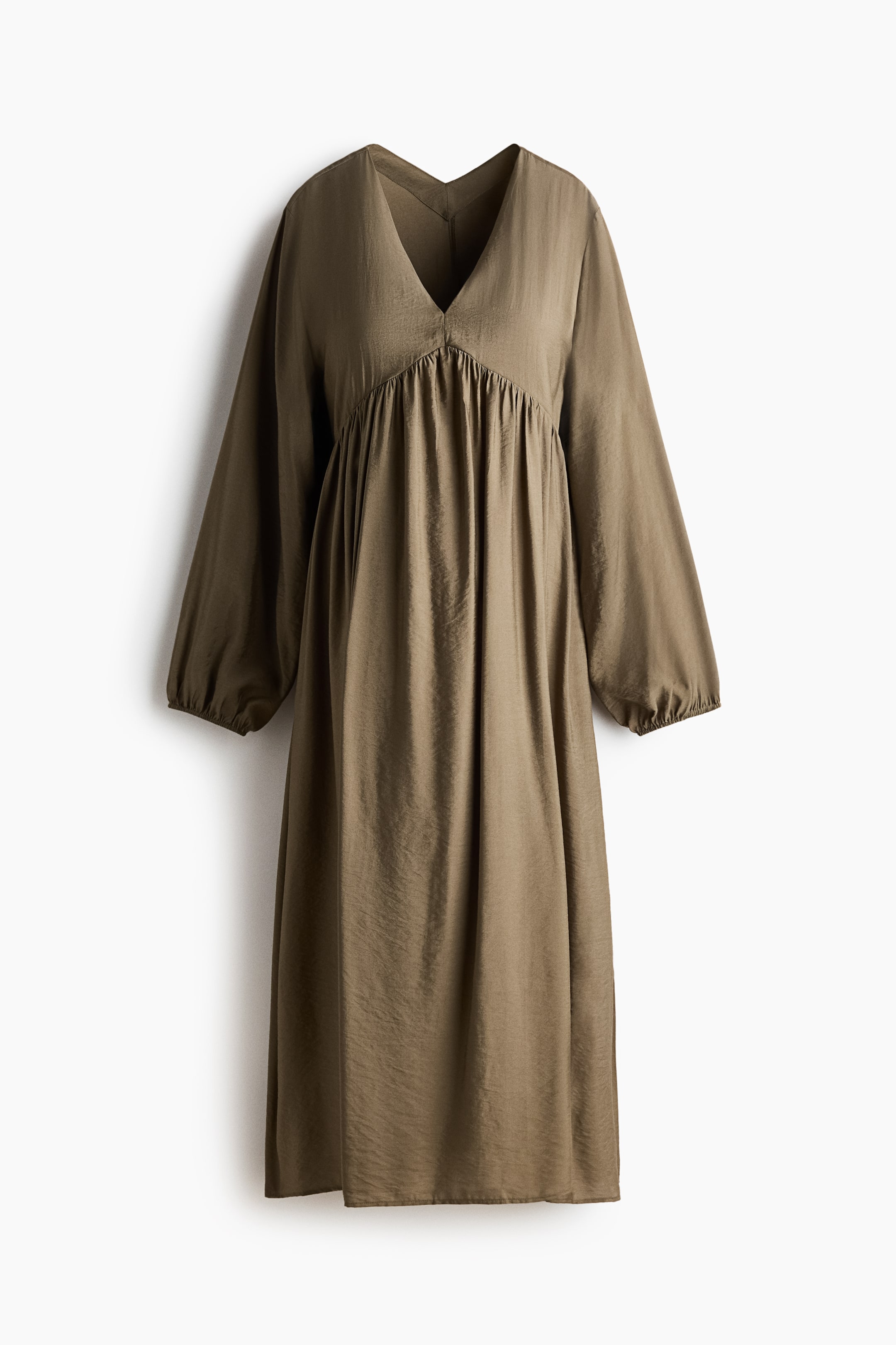 View larger image: The olive green midi dress features a subtly textured fabric with a deep V-neckline and long sleeves. It showcases gathering below the bust, creating a flowing silhouette, and the sleeves end in elasticated cuffs.
