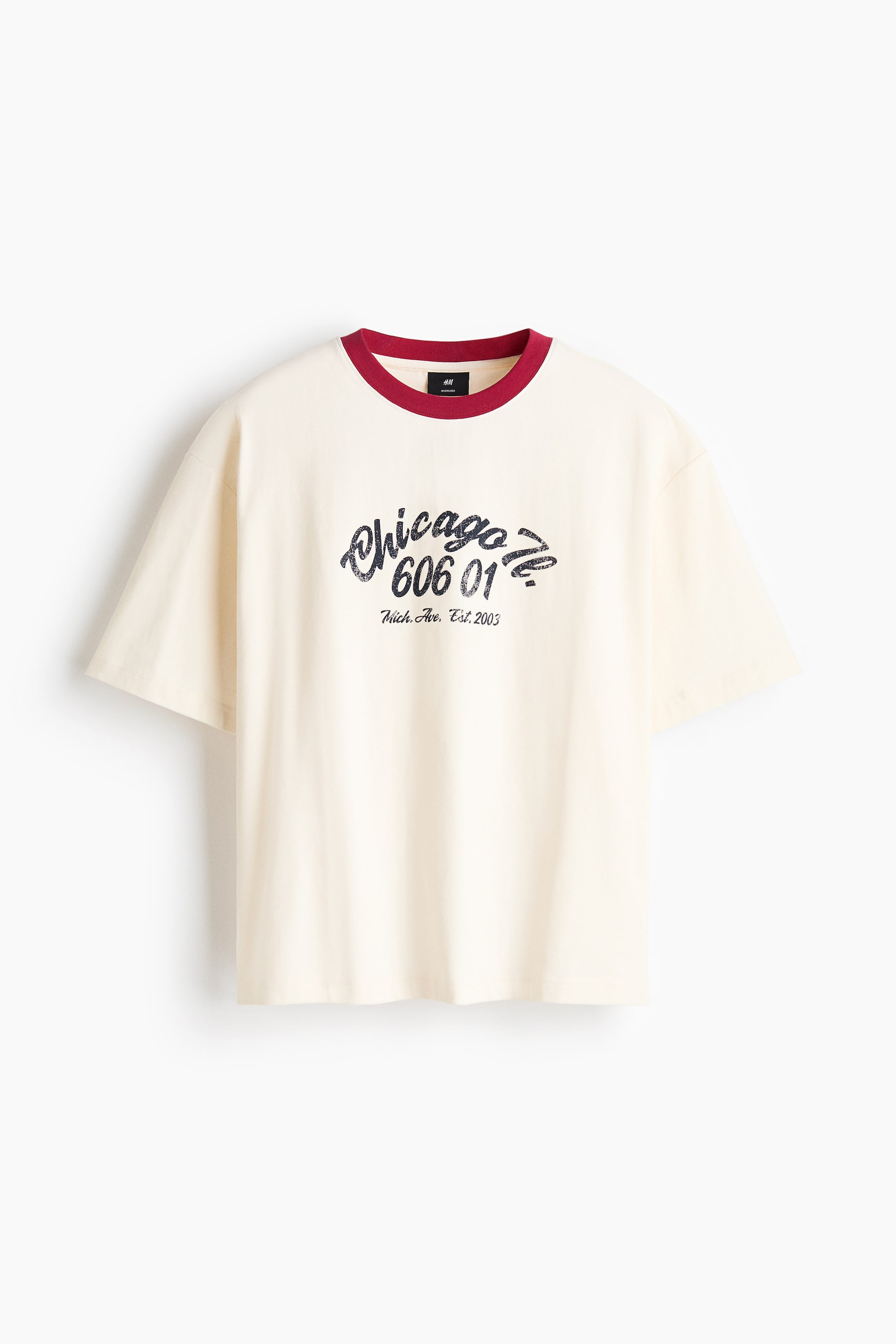 View larger image: A cream-colored ringer T-shirt is shown from the front, featuring a contrasting burgundy ribbed crew neck and an oversized fit with dropped shoulders. The chest displays a distressed dark blue graphic print reading "Chicago Ill." above "606 01" and "Mich. Ave. Est. 2003".