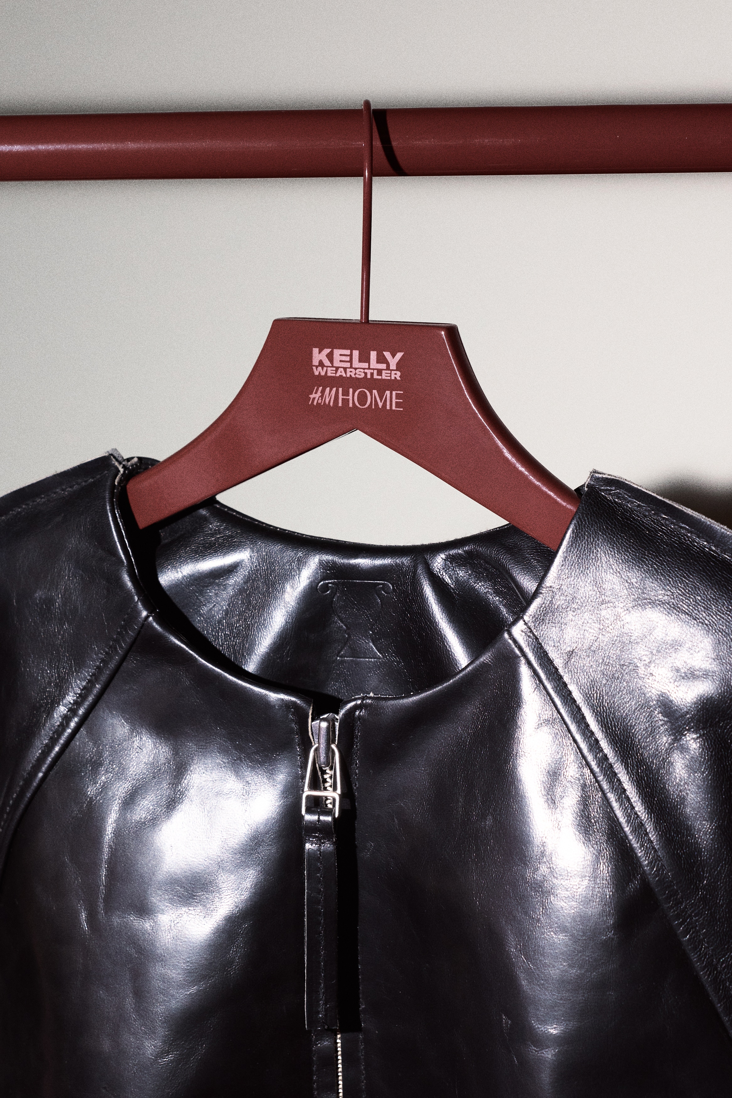 Four dark red wooden clothes hangers are presenting with their front side visible, stacked vertically. Each hanger is featuring a contoured shoulder shape, a matching dark red metal hook, and the text "KELLY H&M HOME" visible on its center.